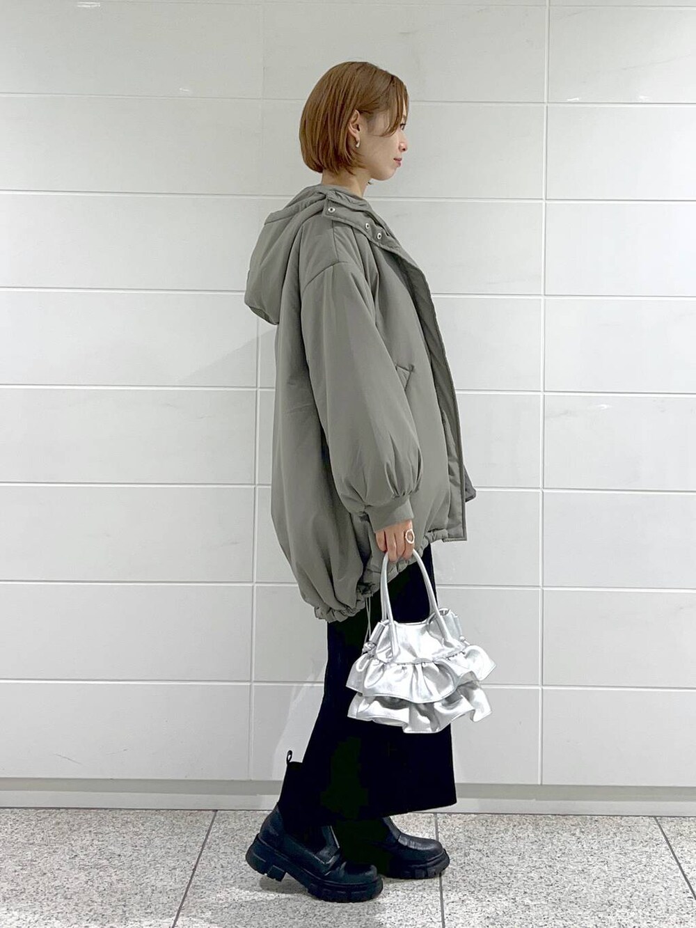 シルバー系のショルダーバッグ、ブラック系のブーツ、ブラック系のスカートを着用したレディースの秋コーディネートの3枚目の写真