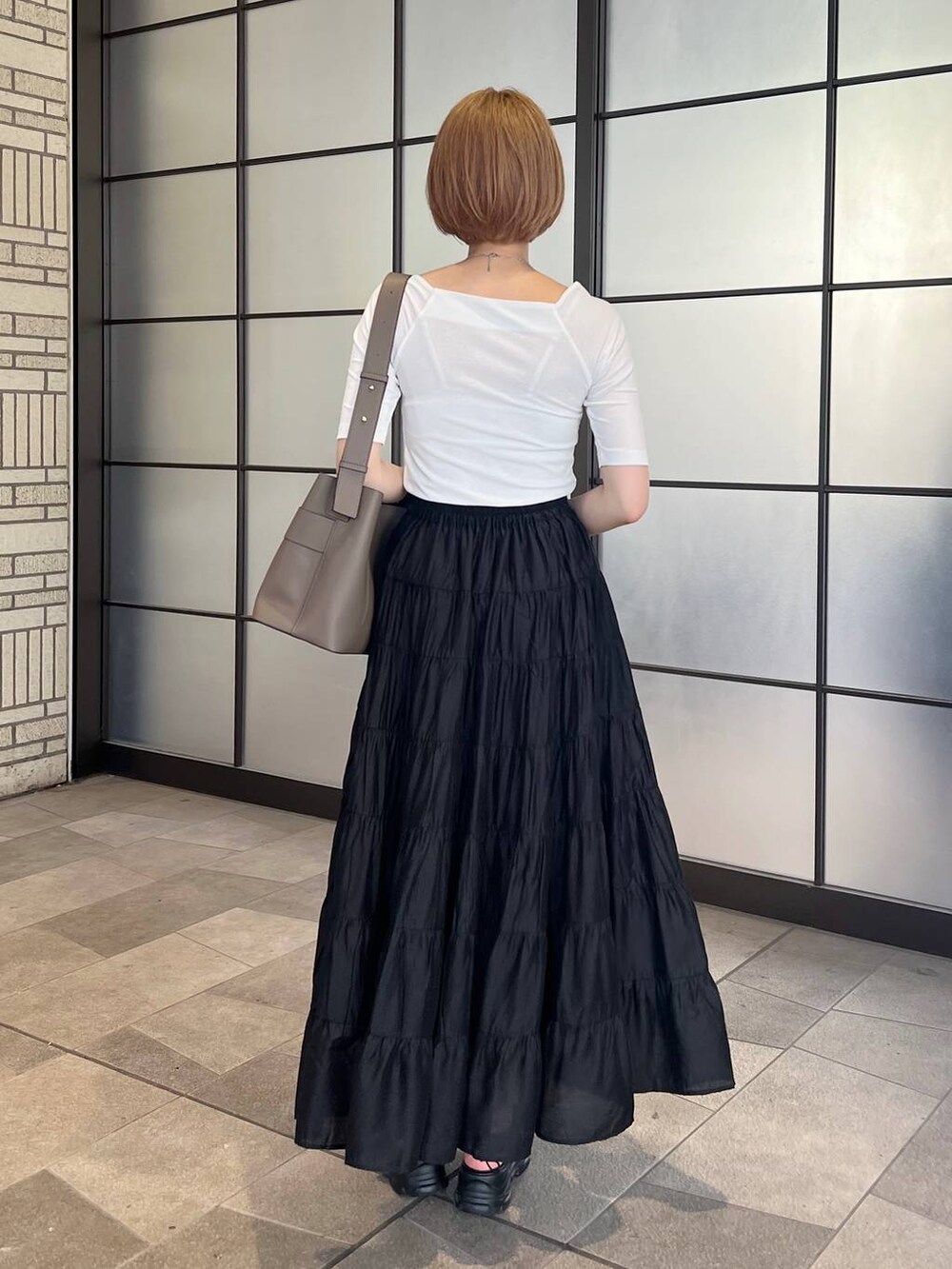 ベージュ系のサンダル、ブラック系のスカート、ホワイト系のTシャツ/カットソーを着用したレディースの夏コーディネートの3枚目の写真