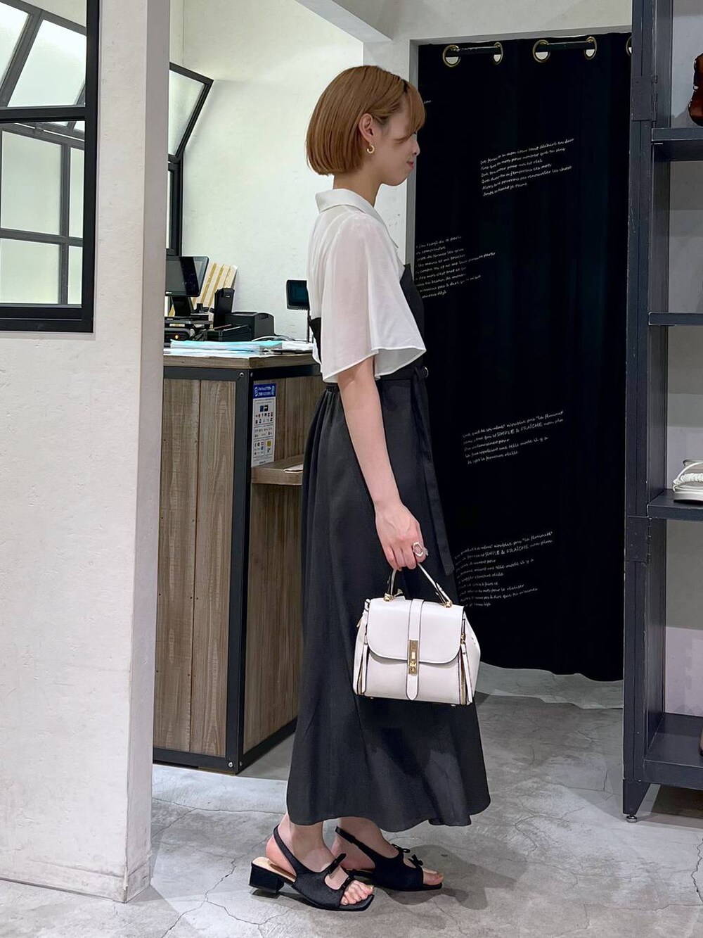 ブラック系のサンダル、グレー系のワンピース、ホワイト系のショルダーバッグを着用したレディースの春コーディネートの3枚目の写真