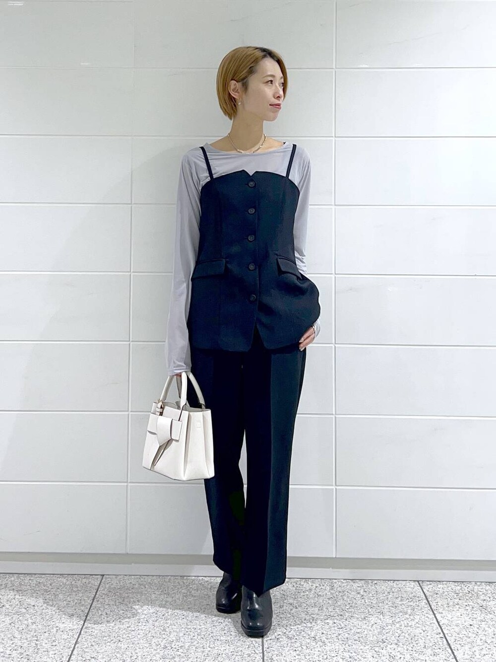 グレー系のTシャツ/カットソー、ブラック系のブーツ、ホワイト系のショルダーバッグを着用したレディースの冬コーディネートの4枚目の写真