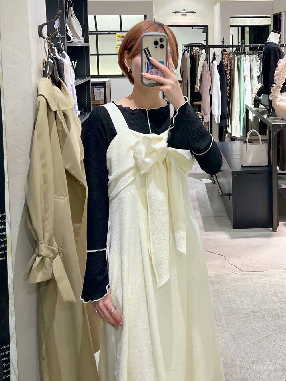 ホワイト系のショルダーバッグ、ベージュ系のトレンチコート、ブラック系のバレエシューズを着用したレディースの春コーディネートの7枚目の写真