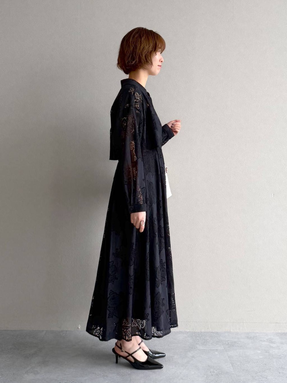 ブラック系のサンダル、ブラック系のワンピース、ホワイト系のショルダーバッグを着用したレディースの春コーディネートの2枚目の写真