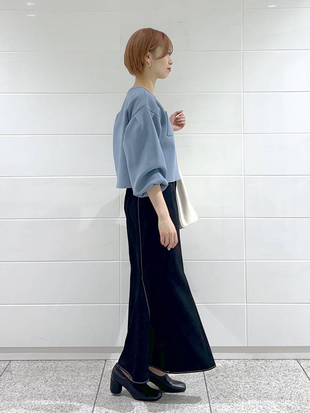 ホワイト系のトートバッグ、ブラック系のパンプス、ブラック系のスカートを着用したレディースの春コーディネートの3枚目の写真