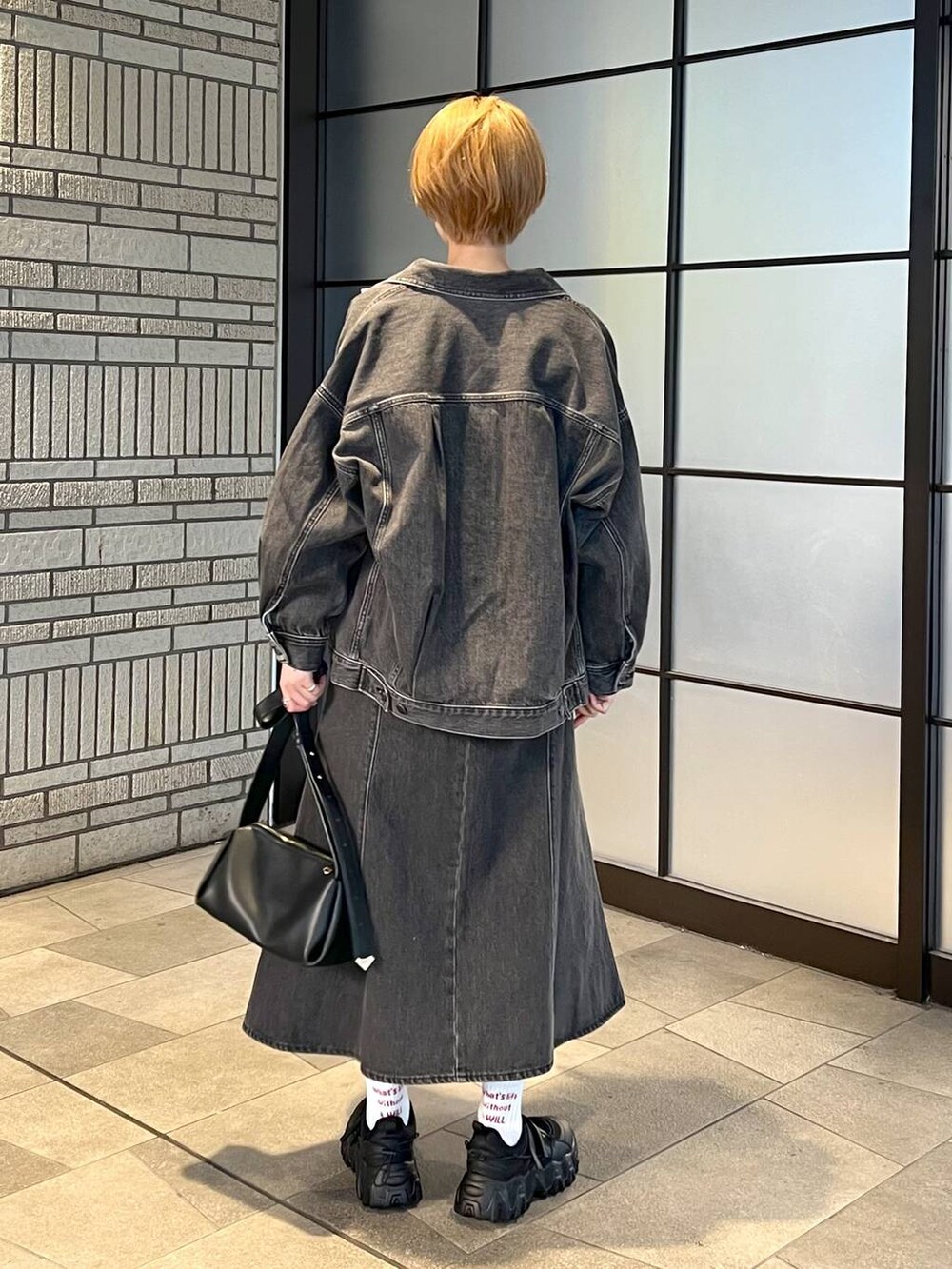 ブラック系のデニムジャケット、ブラック系のジャンパースカート、ブラック系のバレエシューズを着用したレディースの冬コーディネートの3枚目の写真