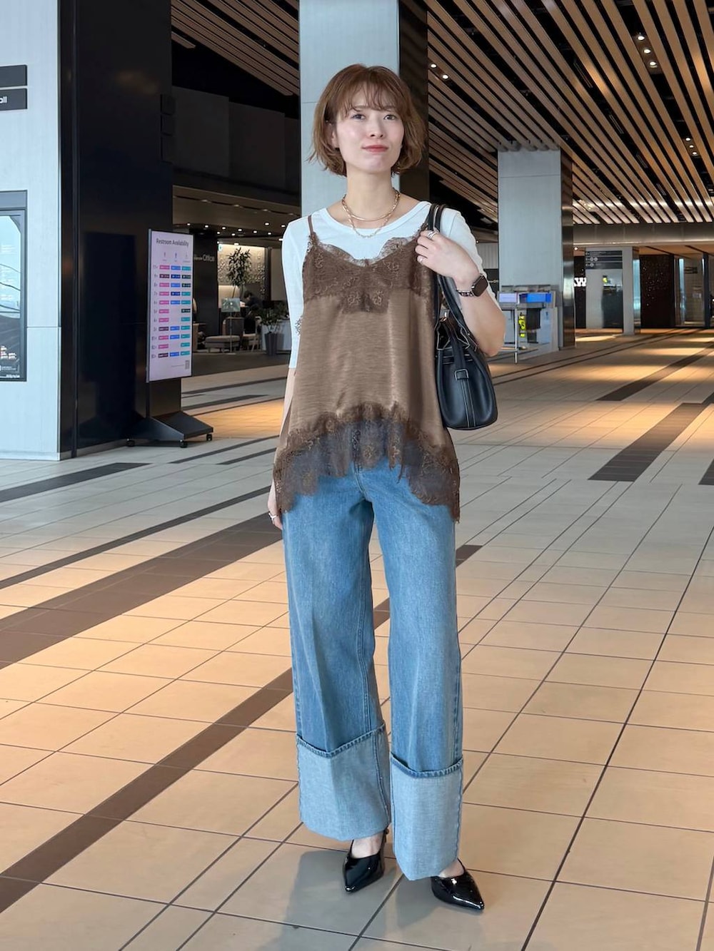 ブラック系のサンダル、ブラウン系のキャミソール、ホワイト系のノーカラージャケットを着用したレディースの春コーディネートの4枚目の写真