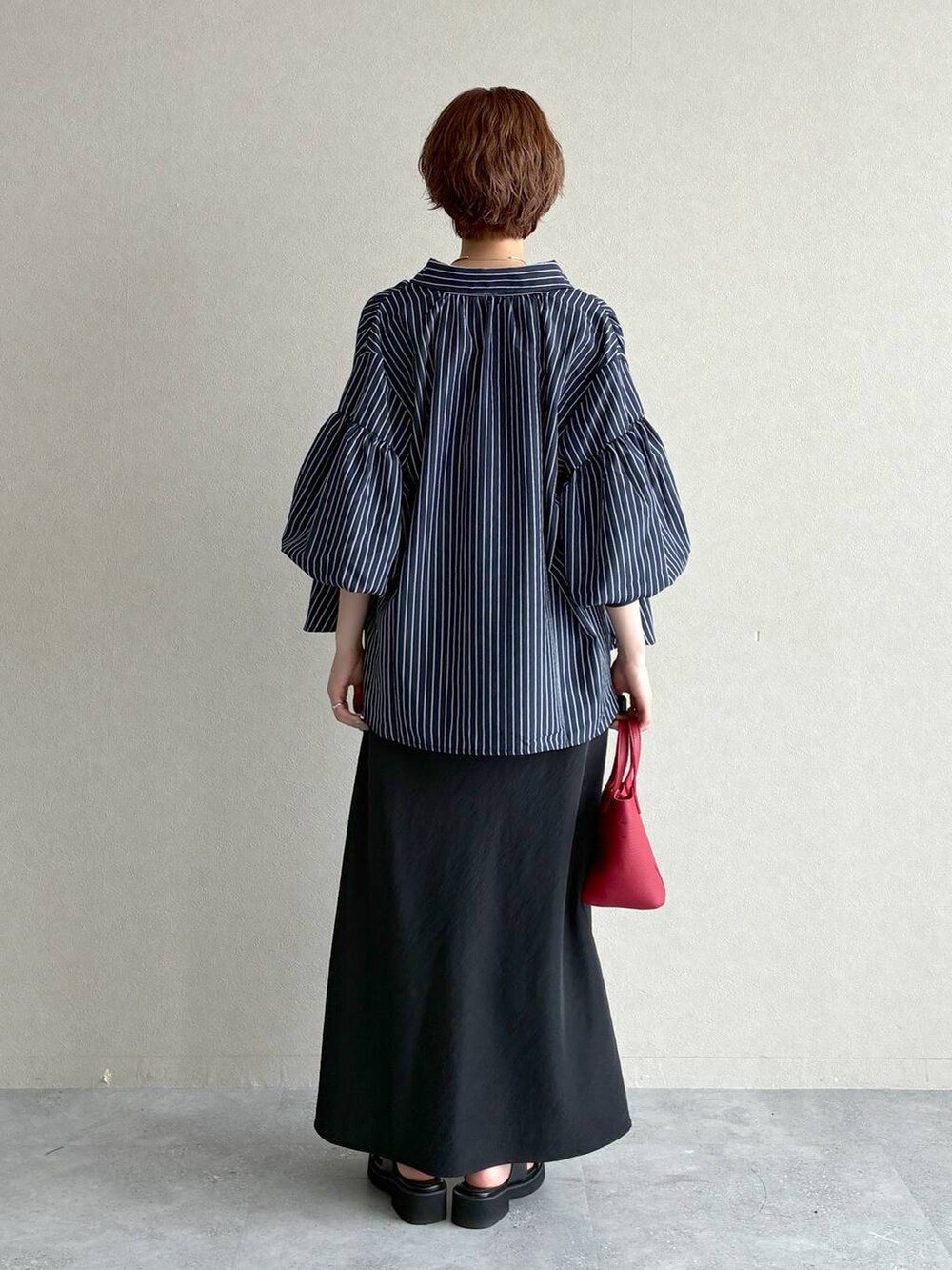 ブラック系のサンダル、ブラック系のスカート、レッド系のショルダーバッグを着用したレディースの夏コーディネートの3枚目の写真