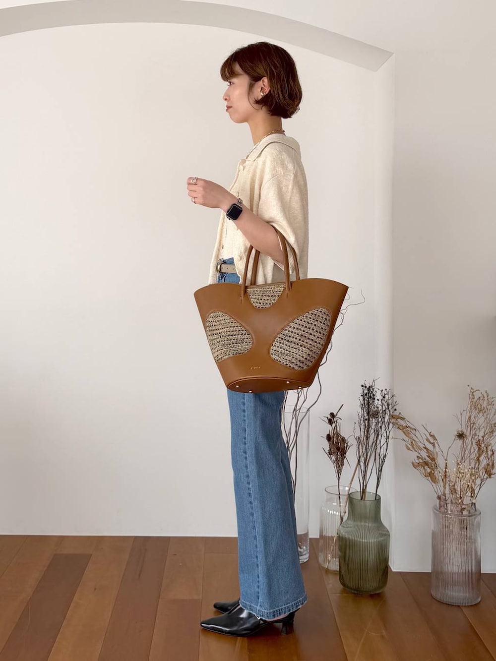 ブラウン系のトートバッグ、ブルー系のデニムパンツ、ブラック系のサンダルを着用したレディースの春コーディネートの2枚目の写真