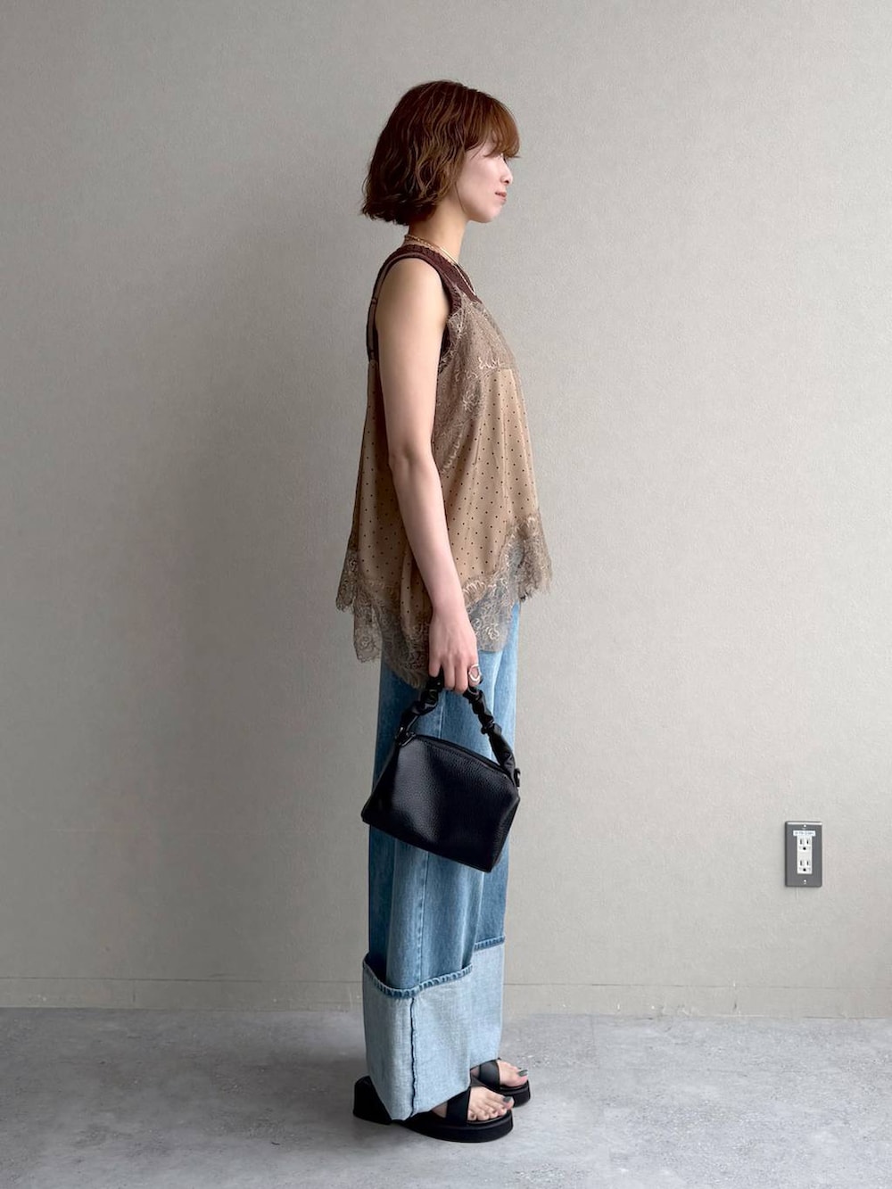 ベージュ系のキャミソール、ブラック系のサンダル、ブルー系のデニムパンツを着用したレディースの春コーディネートの2枚目の写真