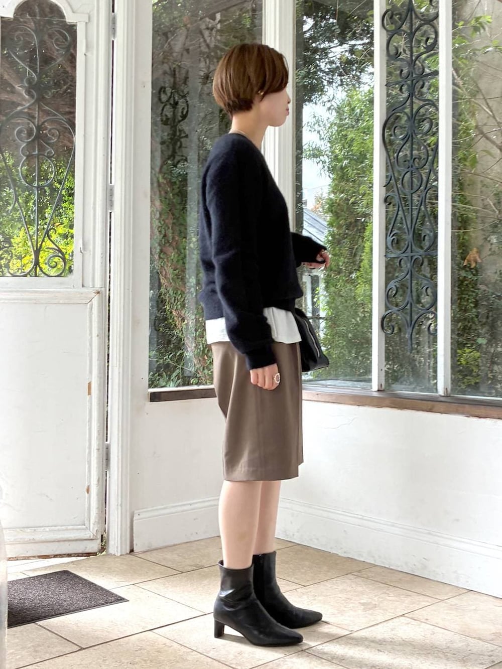 ホワイト系のTシャツ/カットソー、ブラック系のブーツ、ブラック系のトートバッグを着用したレディースの秋コーディネートの2枚目の写真