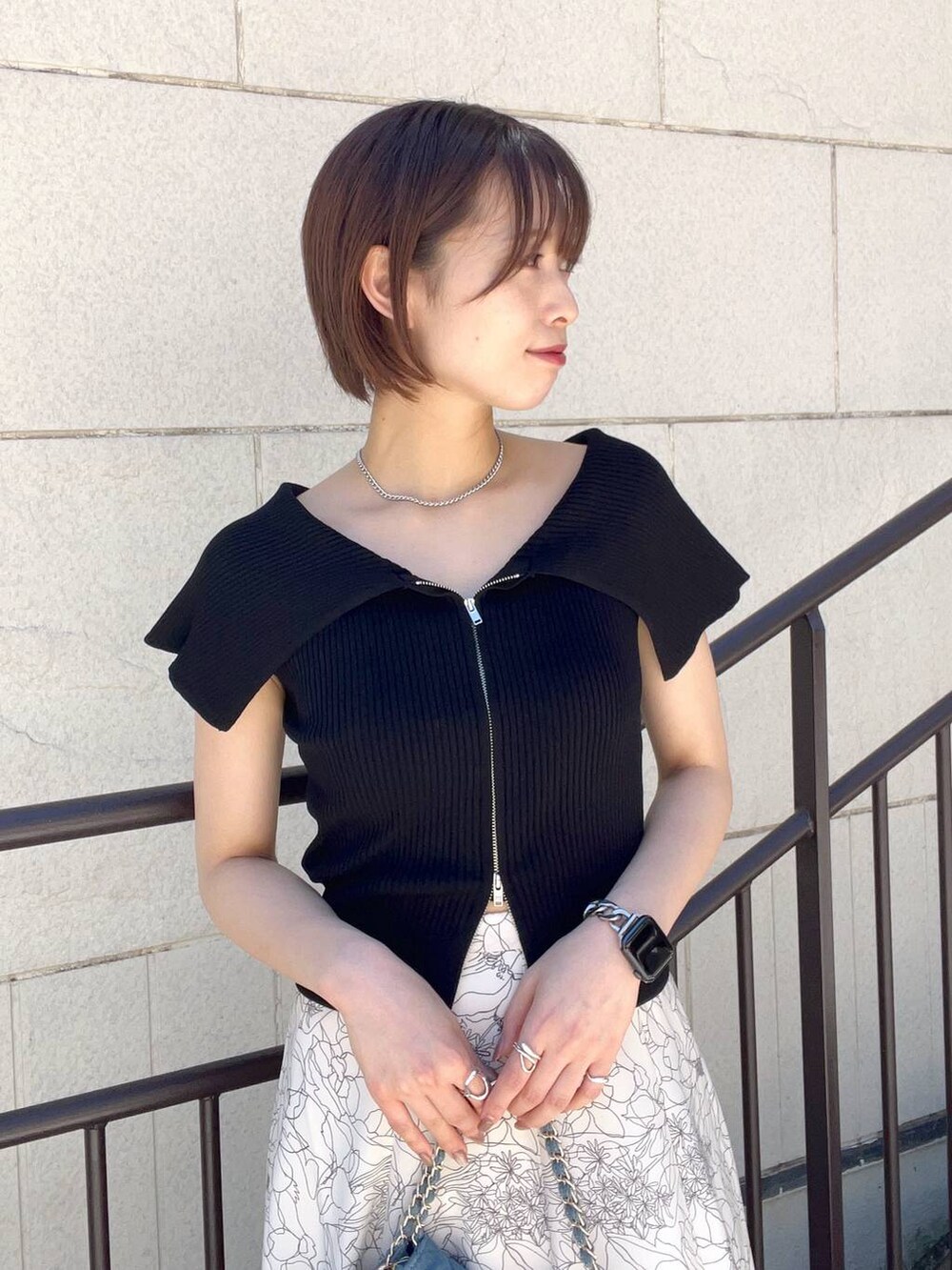 ブラック系のニット/セーター、ブルー系のショルダーバッグ、ホワイト系のスカートを着用したレディースの夏コーディネートの5枚目の写真