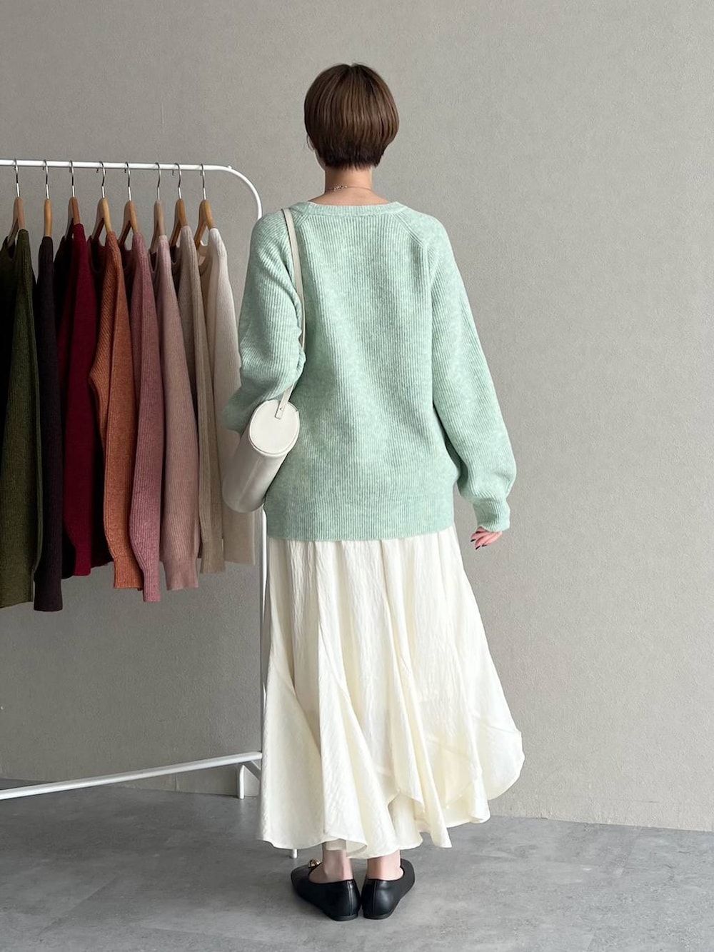 ホワイト系のスカート、ブラック系のブルゾン、ホワイト系のショルダーバッグを着用したレディースの秋コーディネートの6枚目の写真