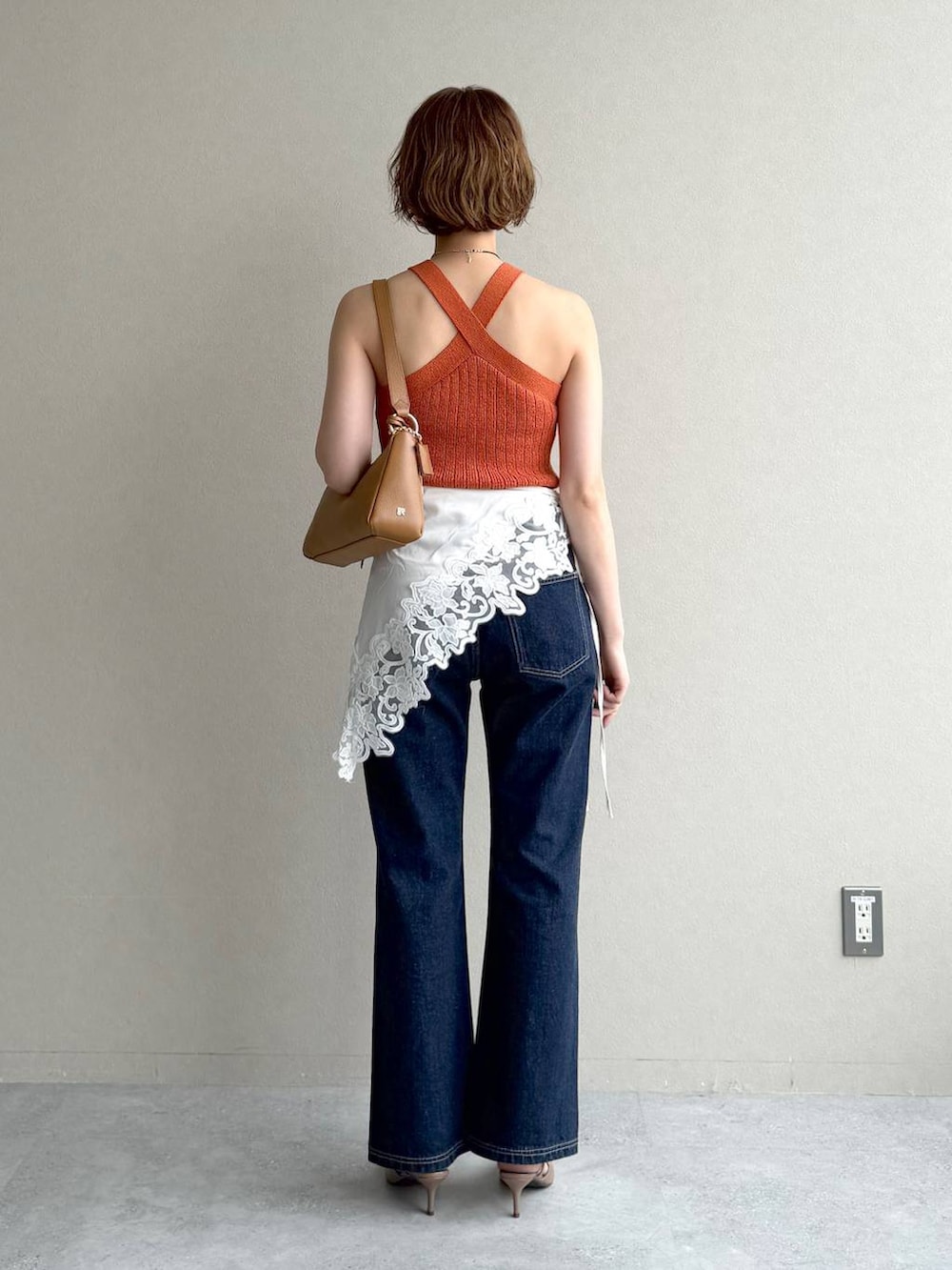 ブルー系のデニムパンツ、ブラウン系のサンダル、イエロー系のショルダーバッグを着用したレディースの春コーディネートの3枚目の写真