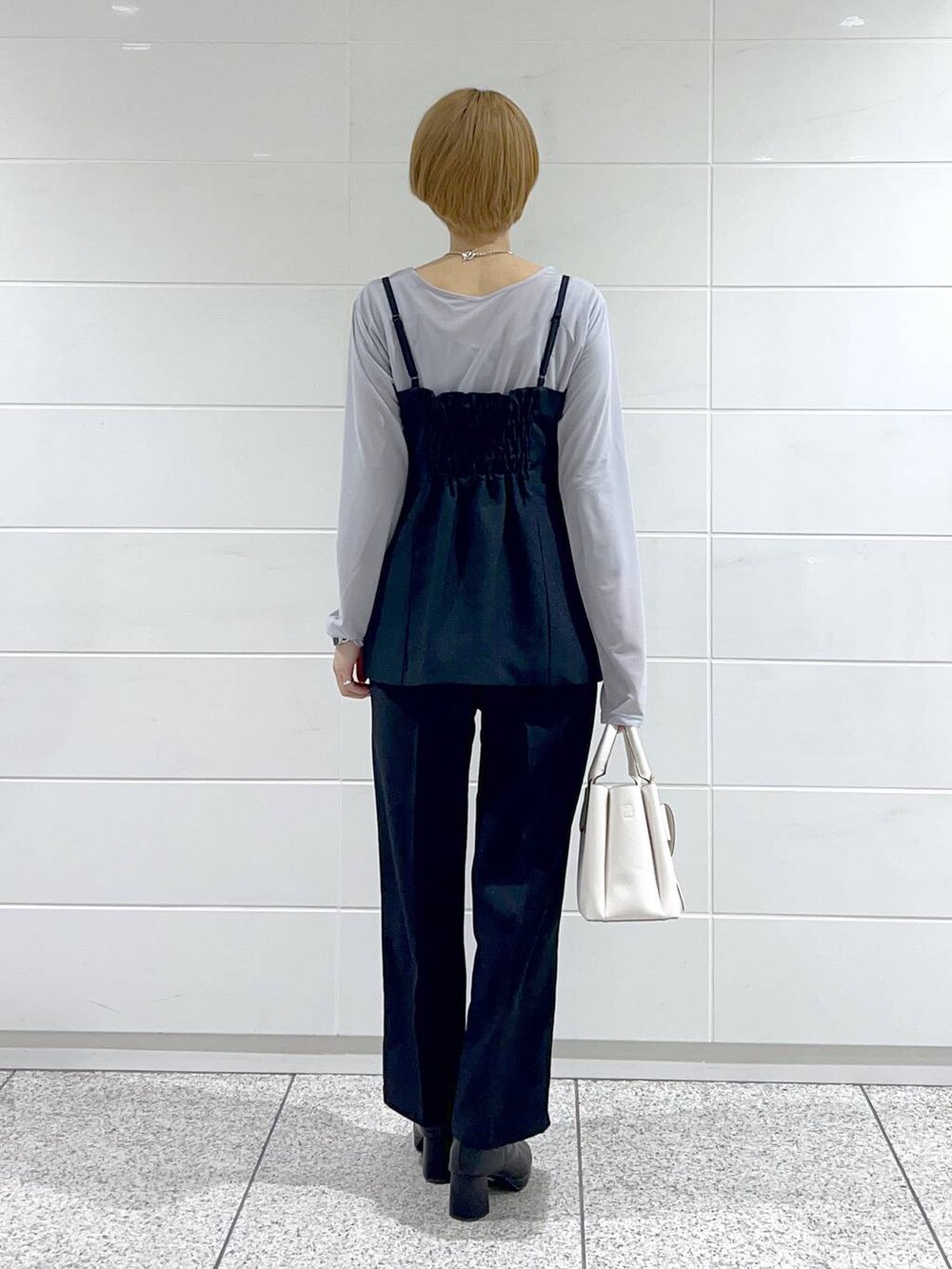 グレー系のTシャツ/カットソー、ブラック系のブーツ、ホワイト系のショルダーバッグを着用したレディースの冬コーディネートの6枚目の写真