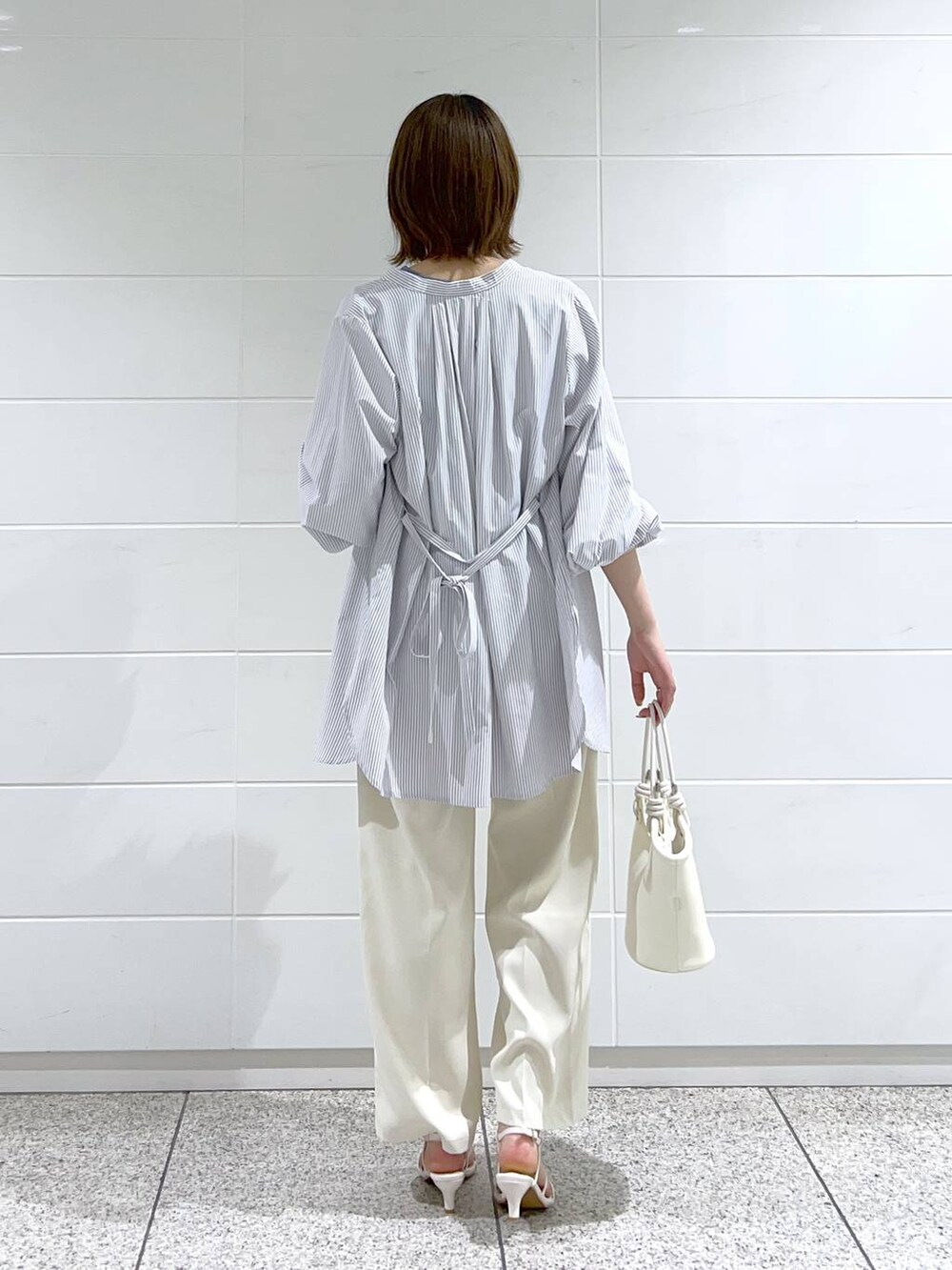 ブルー系のシャツ/ブラウス、ホワイト系のサンダル、ホワイト系のハンドバッグを着用したレディースの春コーディネートの3枚目の写真