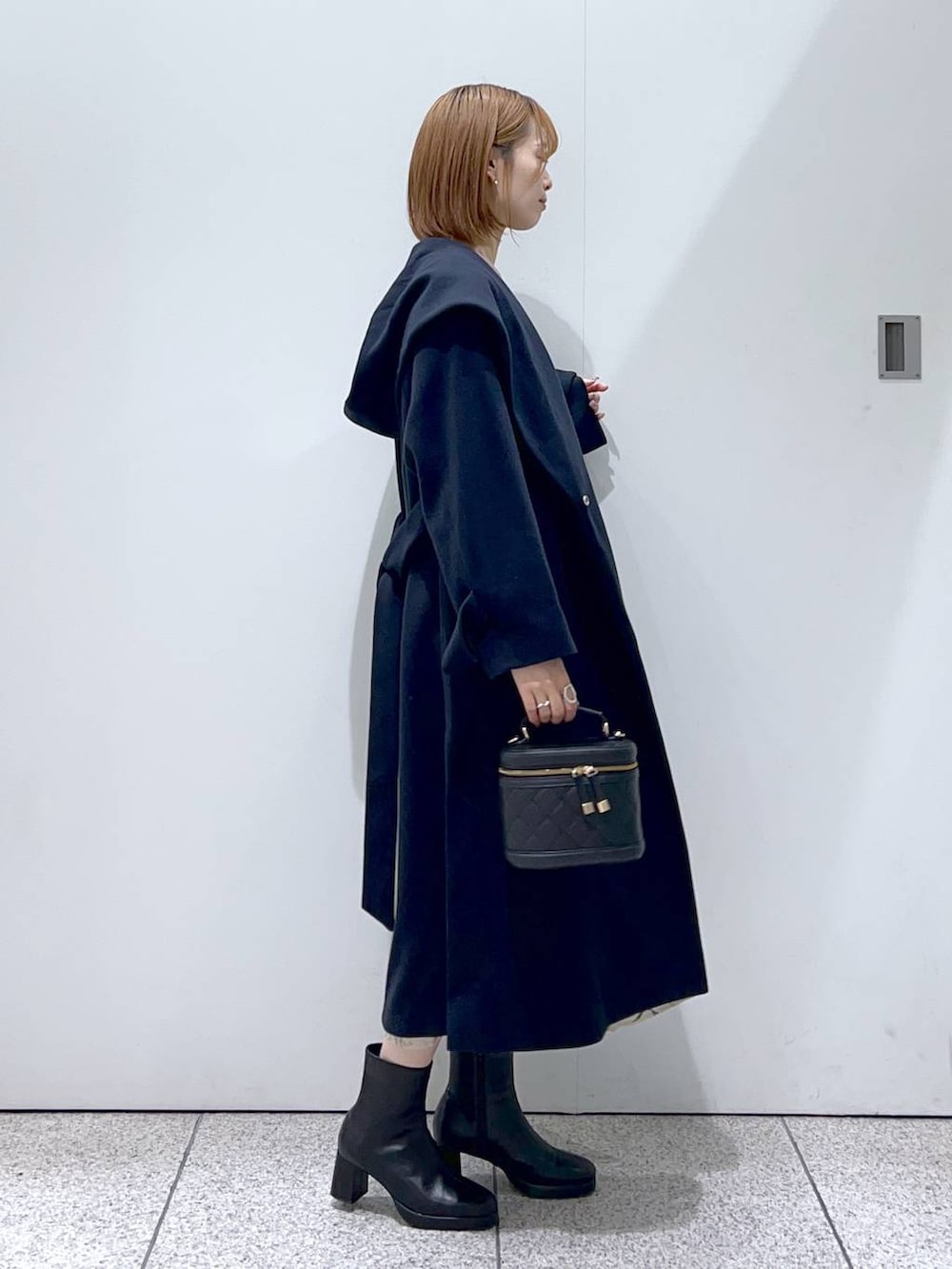 ブルー系のノーカラーコート、ブラック系のブーツ、ベージュ系のワンピースを着用したレディースの秋コーディネートの2枚目の写真