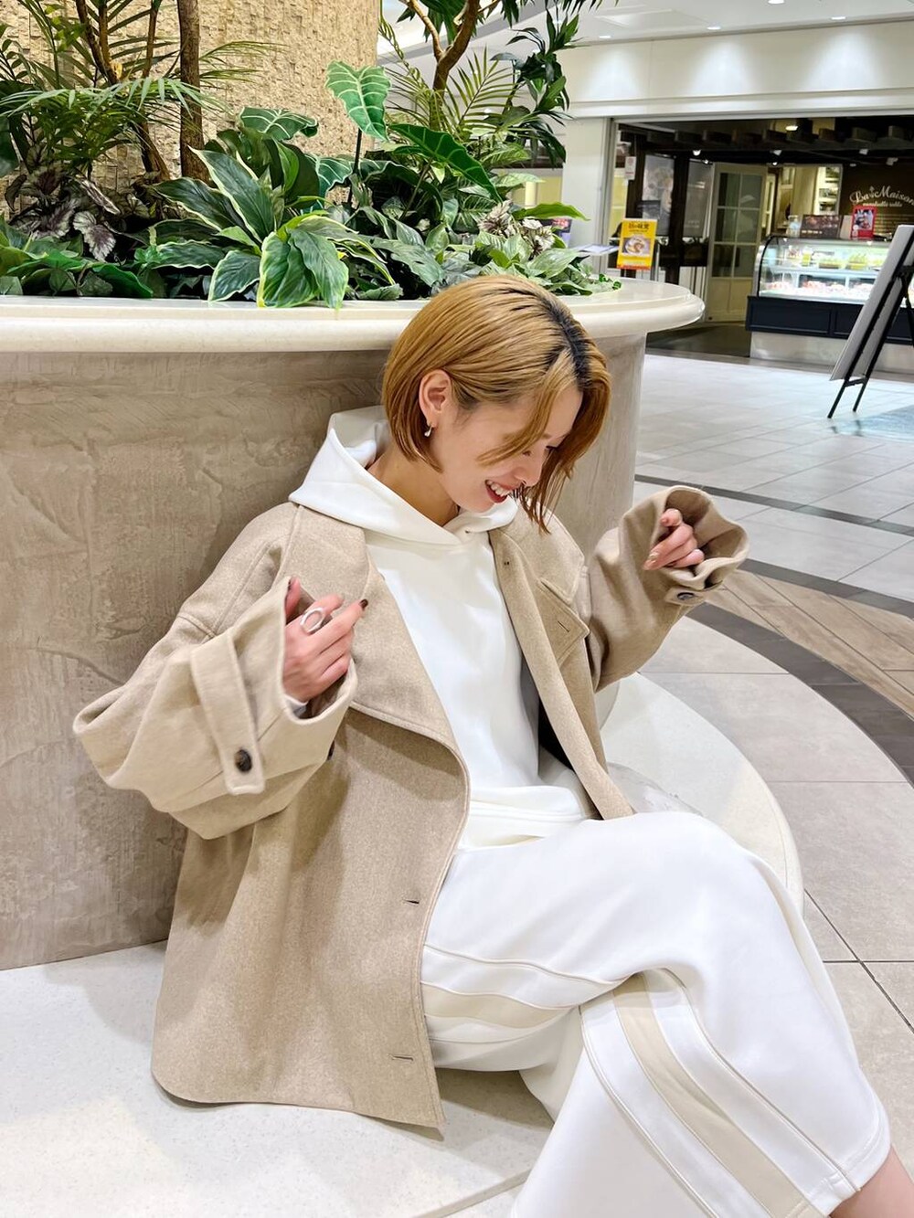 ベージュ系のピーコート、ホワイト系のショルダーバッグ、ブラウン系のブーツを着用したレディースの秋コーディネートの6枚目の写真