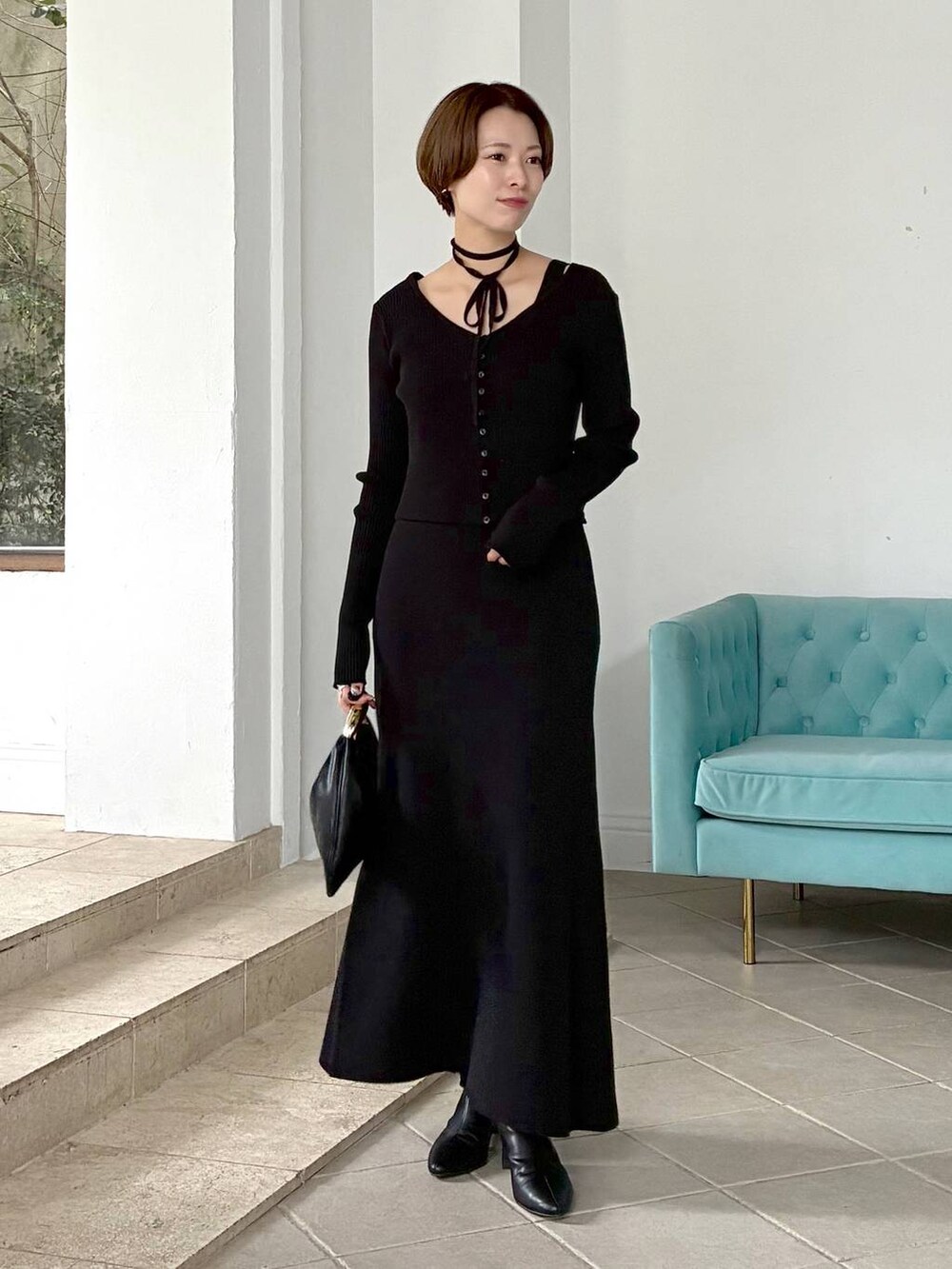 ブラック系のハンドバッグ、ホワイト系のステンカラーコート、ブラック系のブーツを着用したレディースの秋コーディネートの2枚目の写真