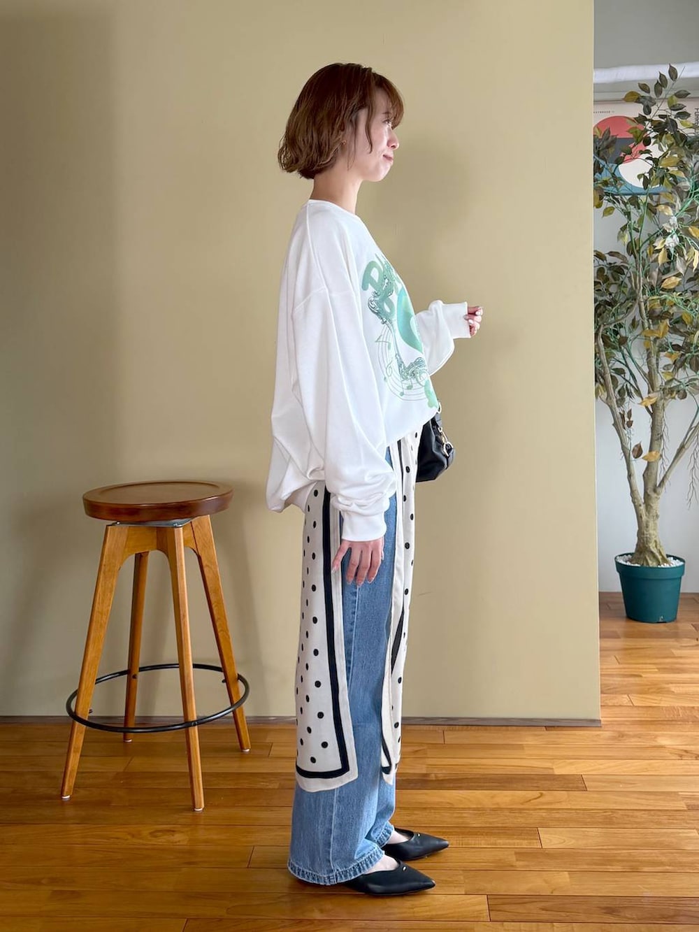 ブラック系のボストンバッグ、ブルー系のデニムパンツ、ブラック系のパンプスを着用したレディースの春コーディネートの6枚目の写真