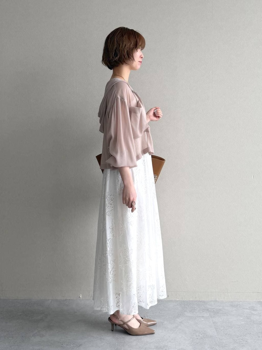 ベージュ系のパーカー、ブラウン系のトートバッグ、ホワイト系のワンピースを着用したレディースの春コーディネートの2枚目の写真