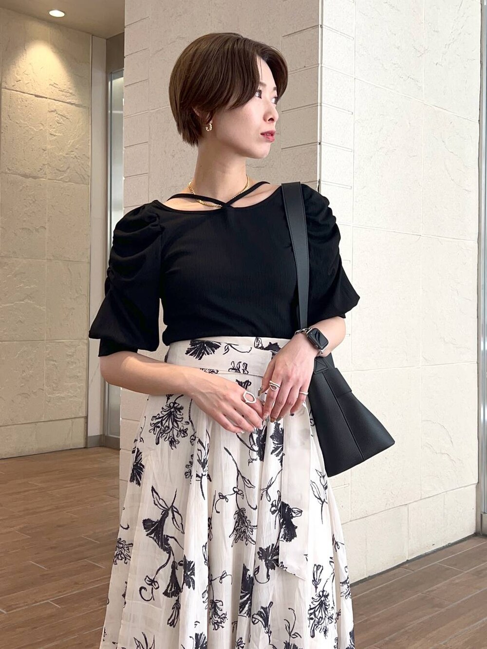 ブラック系のショルダーバッグ、ブラック系のTシャツ/カットソー、ホワイト系のスカートを着用したレディースの夏コーディネートの4枚目の写真