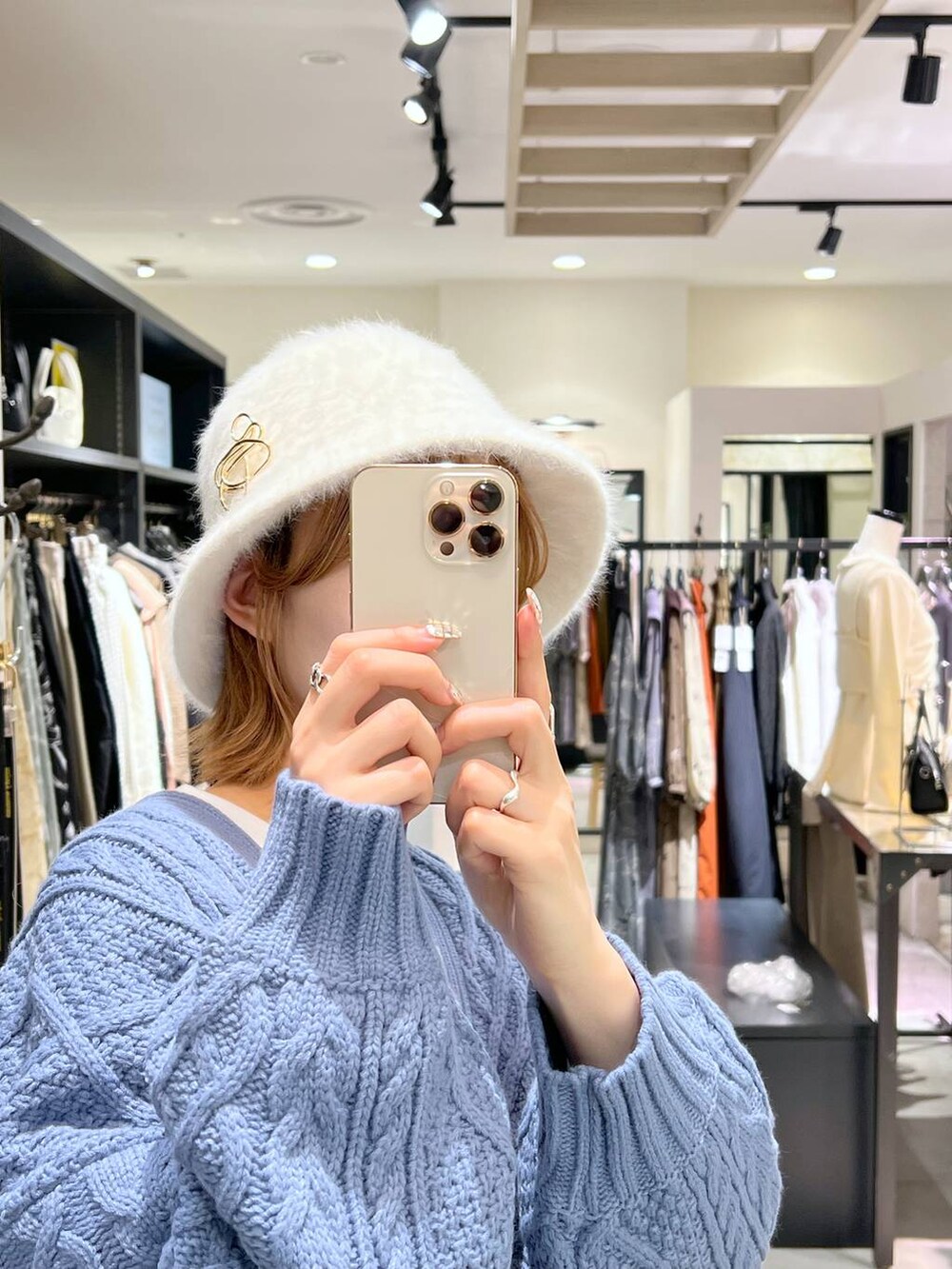 ブラック系のハンドバッグ、ホワイト系のブーツ、ブルー系のカーディガン/ボレロを着用したレディースの秋コーディネートの4枚目の写真