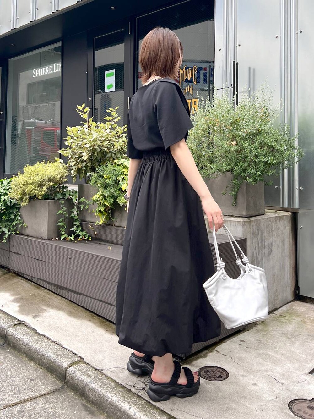 シルバー系のハンドバッグ、ブラック系のサンダル、ブラック系のスカートを着用したレディースの春コーディネートの2枚目の写真
