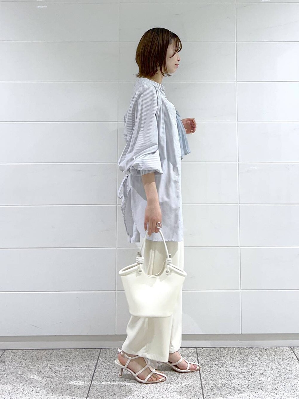 ブルー系のシャツ/ブラウス、ホワイト系のサンダル、ホワイト系のハンドバッグを着用したレディースの春コーディネートの2枚目の写真