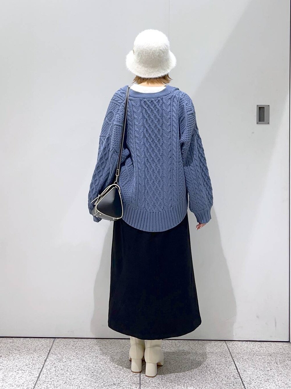 ブラック系のハンドバッグ、ホワイト系のブーツ、ブルー系のカーディガン/ボレロを着用したレディースの秋コーディネートの3枚目の写真