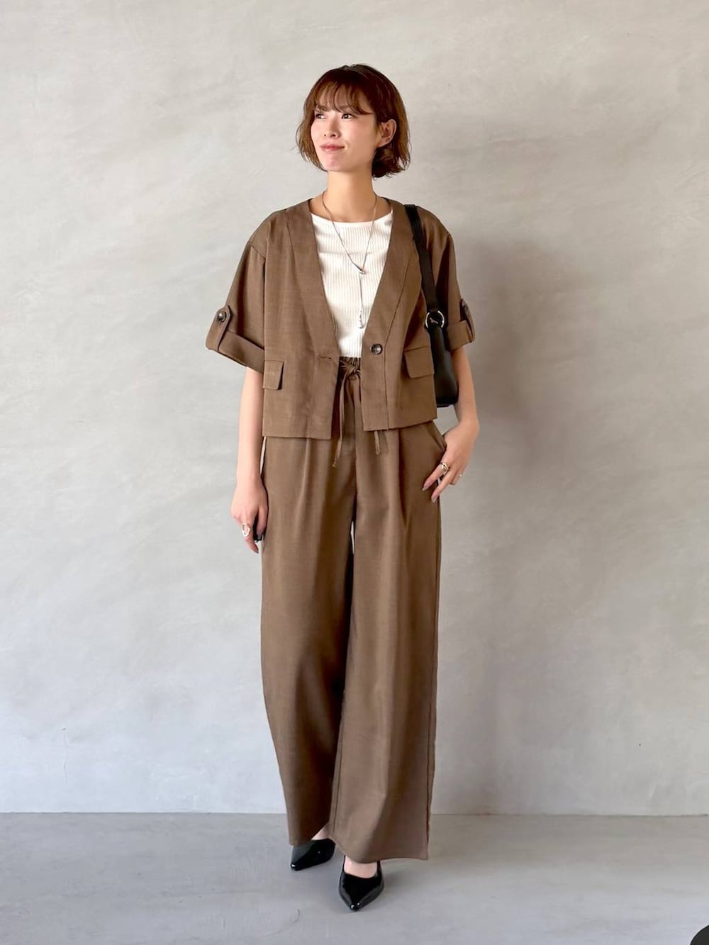 ブラック系のサンダル、ブラック系のショルダーバッグ、ブラウン系のセットアップを着用したレディースの春コーディネートの5枚目の写真