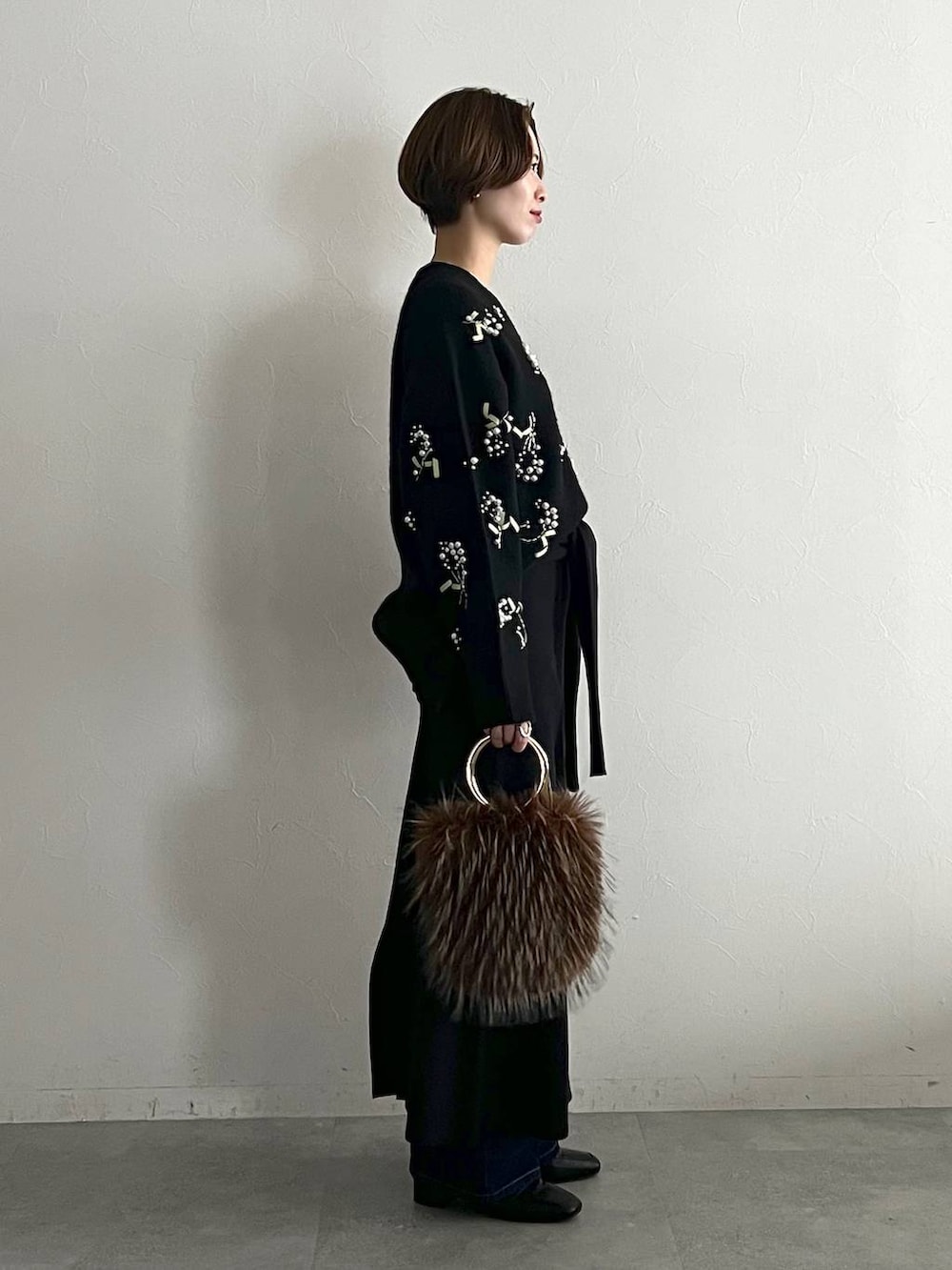 ブラック系のニット/セーター、ブルー系のデニムパンツ、ブラック系のローファーを着用したレディースの秋コーディネートの2枚目の写真