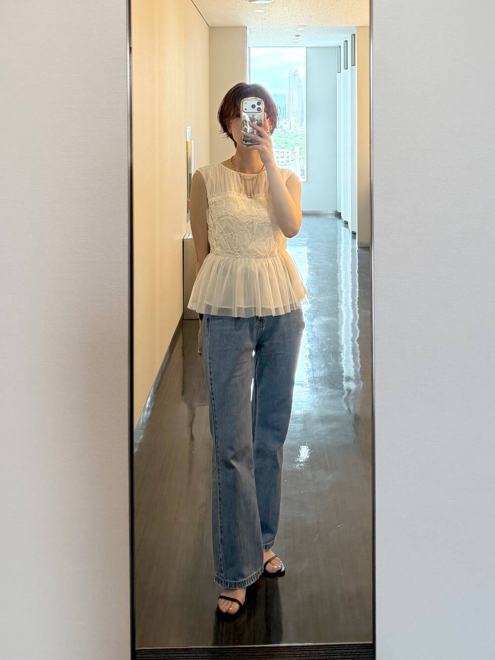 ブラック系のハンドバッグ、ブルー系のデニムパンツを着用したレディースの夏コーディネートの8枚目の写真