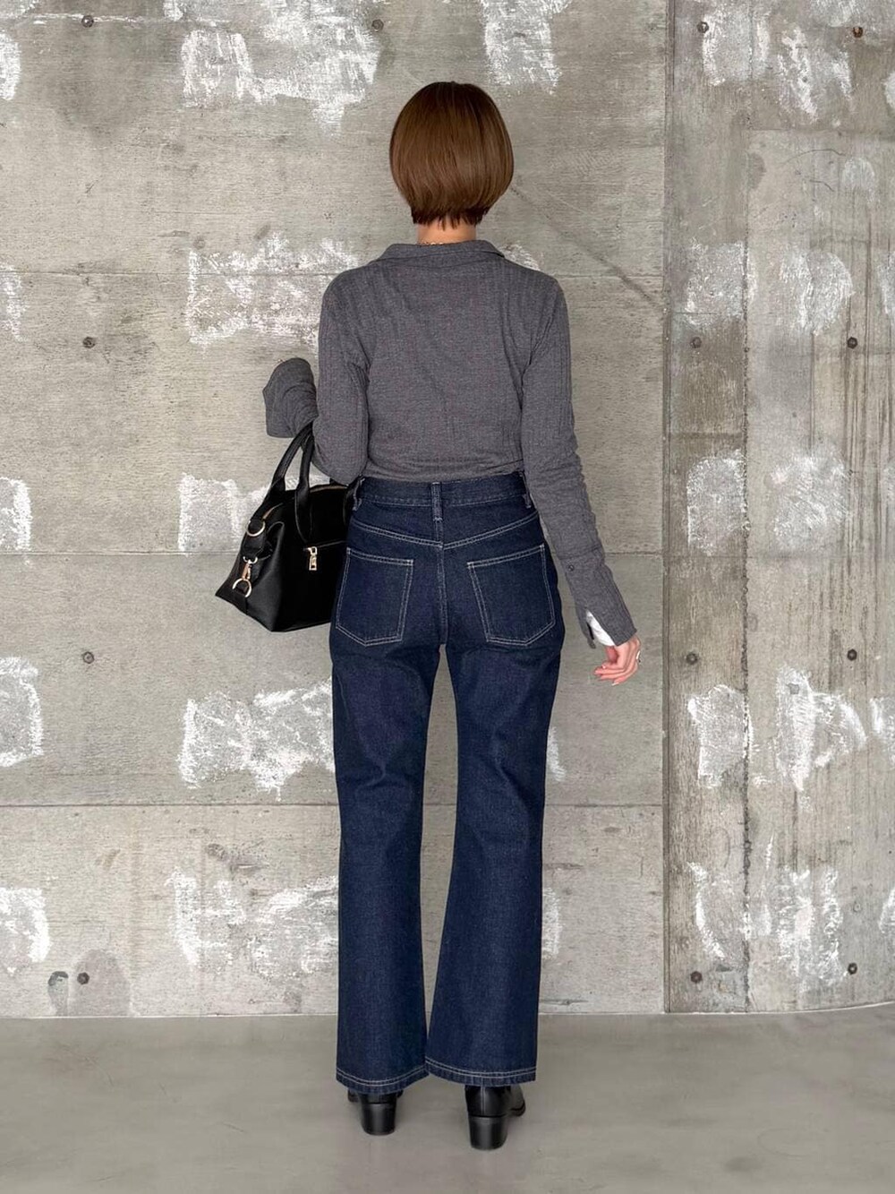 ブラック系のボストンバッグ、ブラック系のブーツ、ブルー系のデニムパンツを着用したレディースの冬コーディネートの3枚目の写真