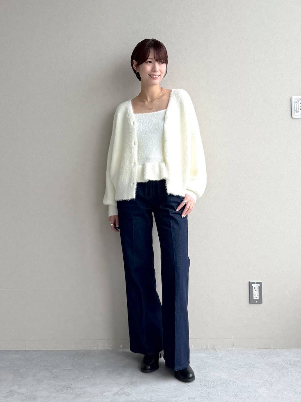 ブルー系のデニムパンツ、ホワイト系のカーディガン/ボレロ、ブラック系のボストンバッグを着用したレディースの秋コーディネートの5枚目の写真