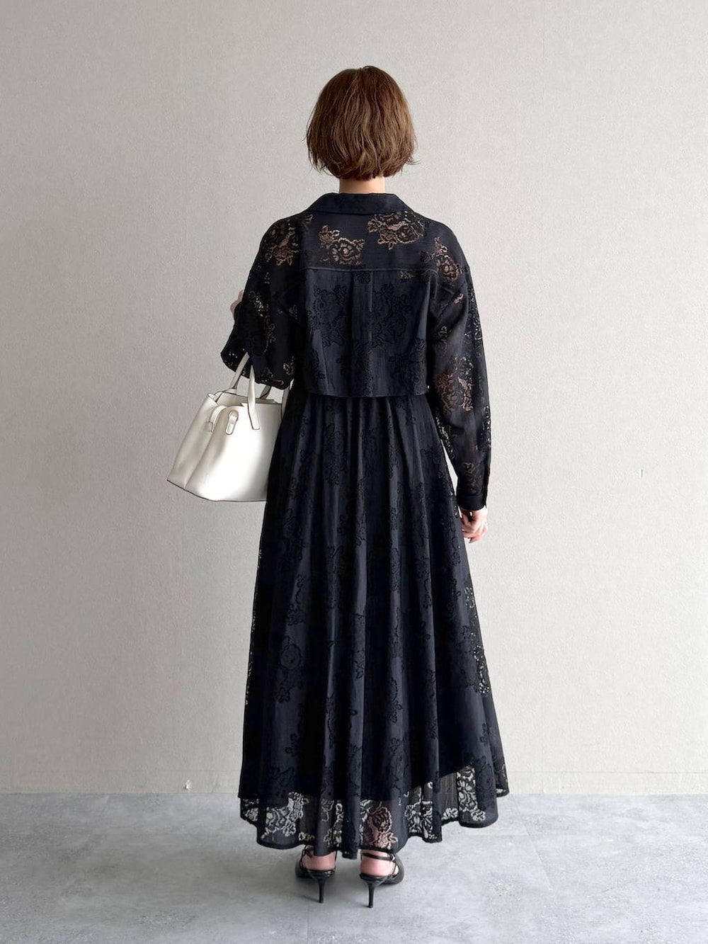 ブラック系のサンダル、ブラック系のワンピース、ホワイト系のショルダーバッグを着用したレディースの春コーディネートの3枚目の写真