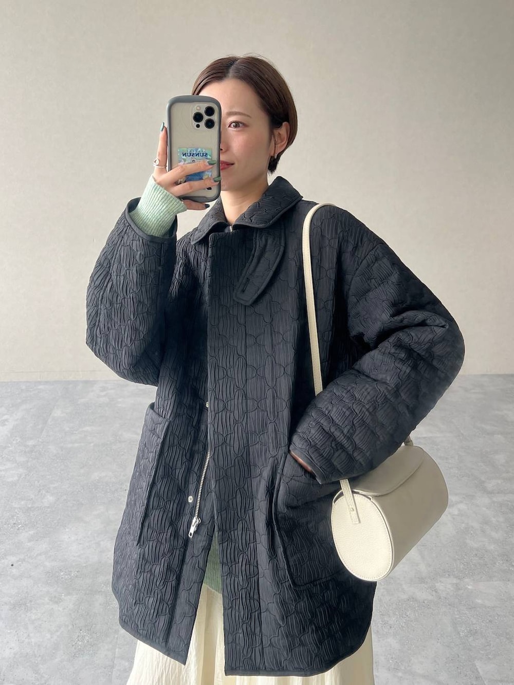 ホワイト系のスカート、ブラック系のブルゾン、ホワイト系のショルダーバッグを着用したレディースの秋コーディネートの7枚目の写真