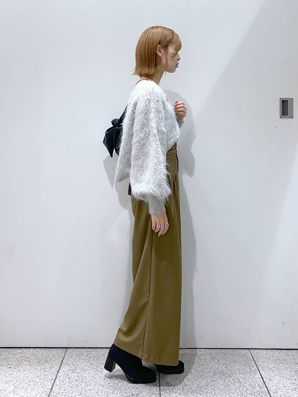 グレー系のカーディガン/ボレロ、ブラック系のブーツ、ブラック系のハンドバッグを着用したレディースの秋コーディネートの2枚目の写真