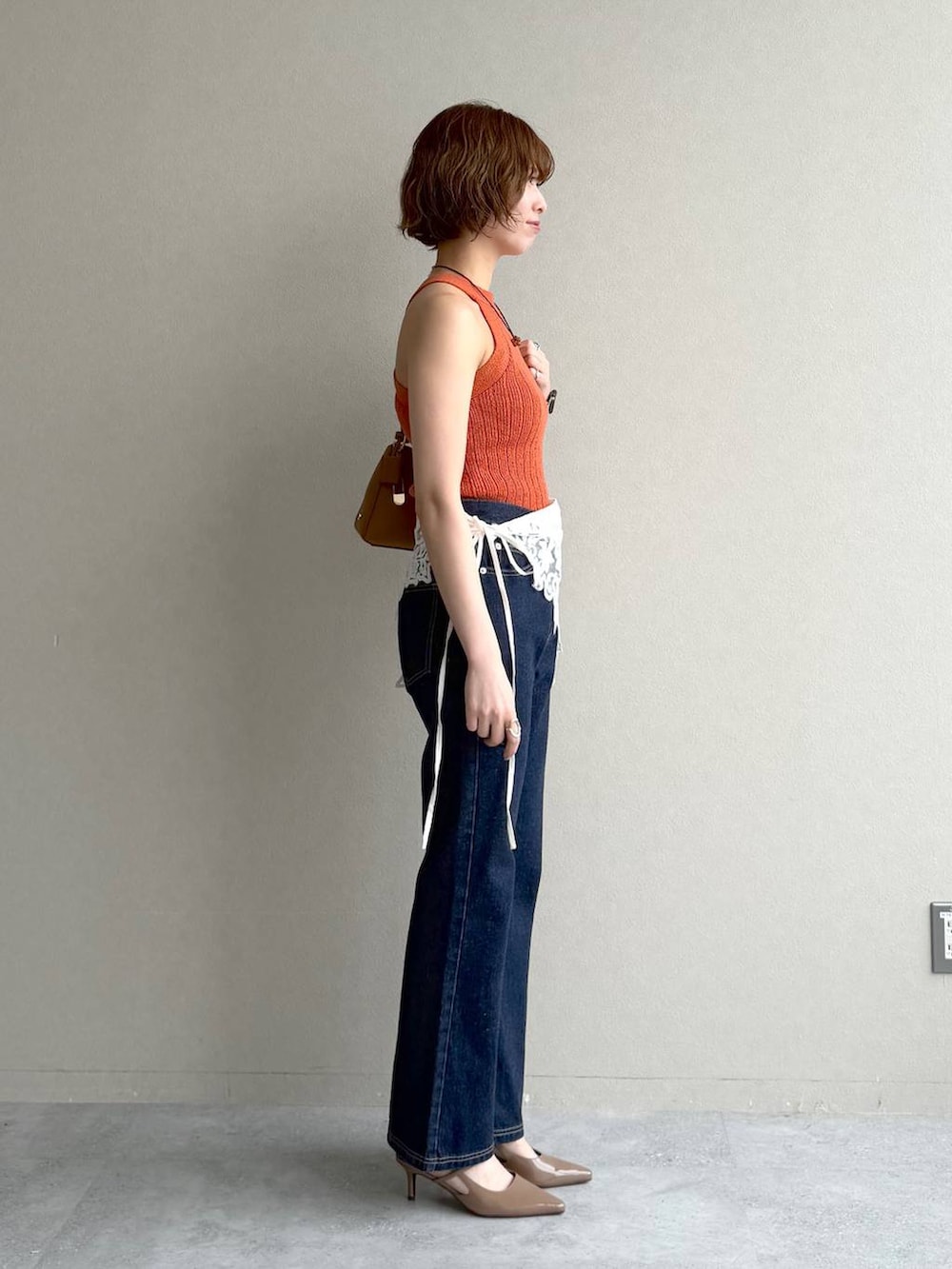 ブルー系のデニムパンツ、ブラウン系のサンダル、イエロー系のショルダーバッグを着用したレディースの春コーディネートの2枚目の写真