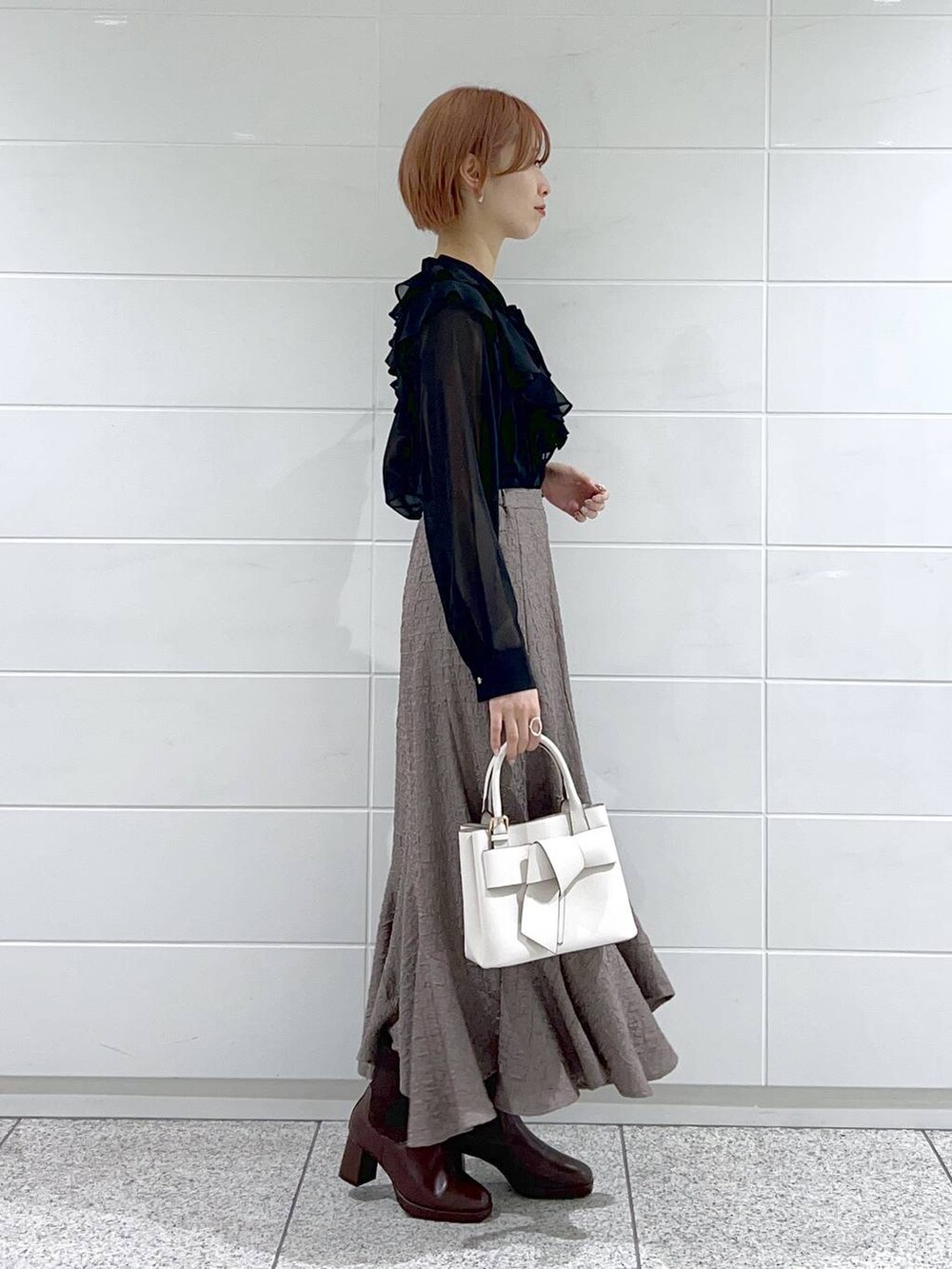 ブラウン系のブーツ、ホワイト系のショルダーバッグ、ブラック系のシャツ/ブラウスを着用したレディースの冬コーディネートの3枚目の写真