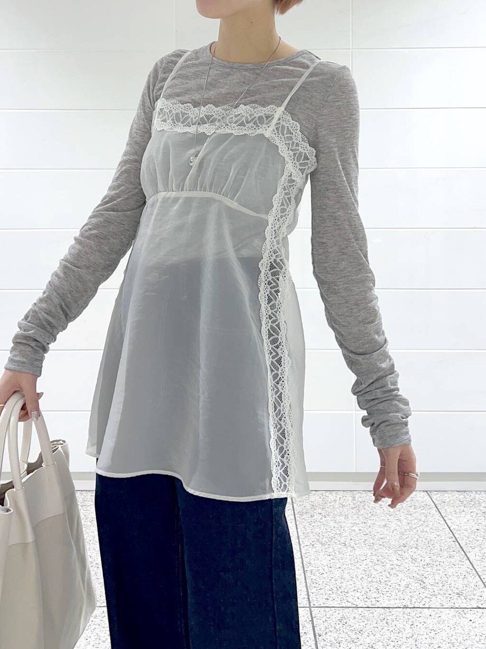 ホワイト系のトートバッグ、ブルー系のデニムパンツ、ブラック系のバレエシューズを着用したレディースの冬コーディネートの4枚目の写真