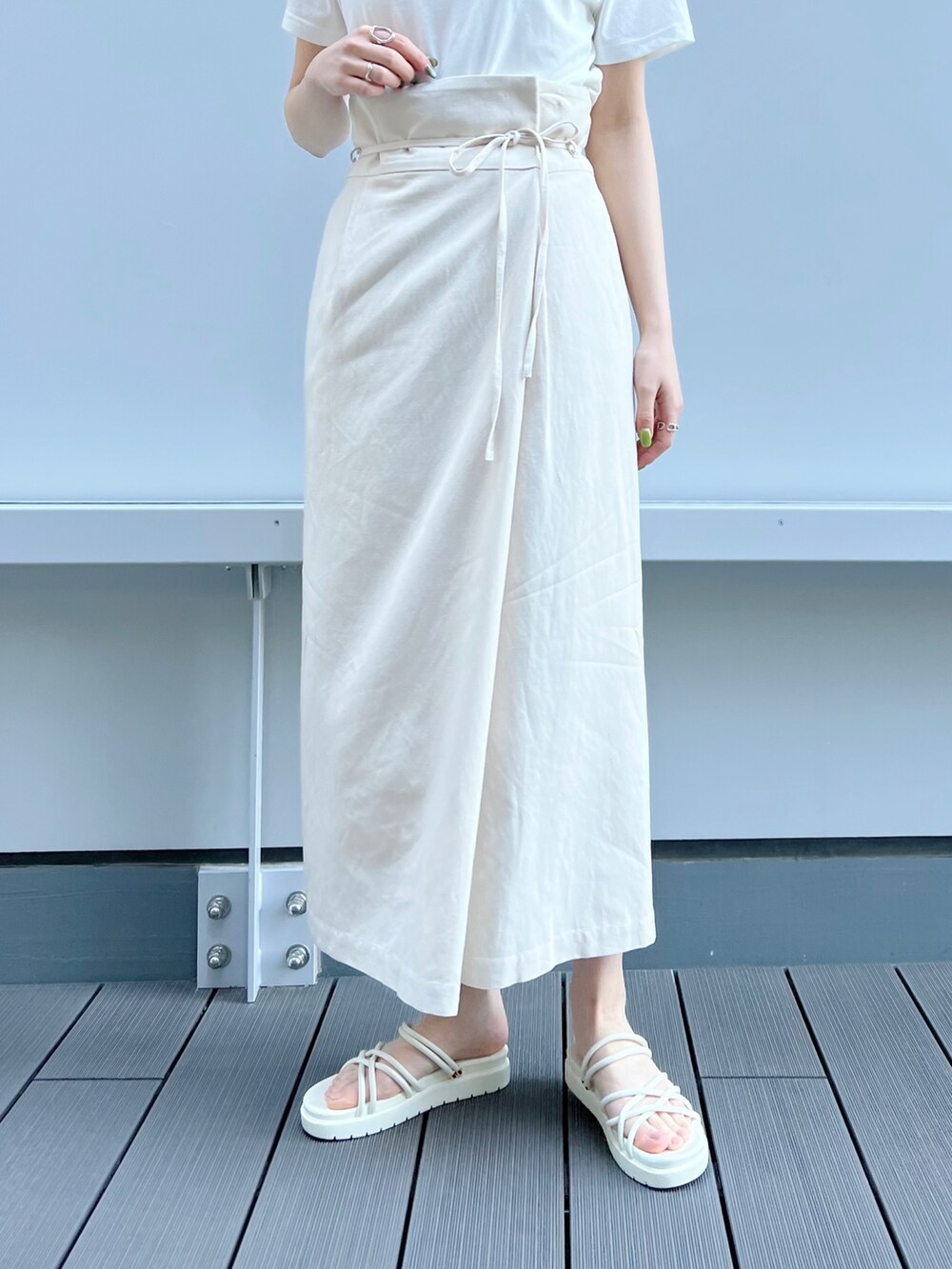 ベージュ系のテーラードジャケット、ホワイト系のスカート、ホワイト系のサンダルを着用したレディースの春コーディネートの5枚目の写真