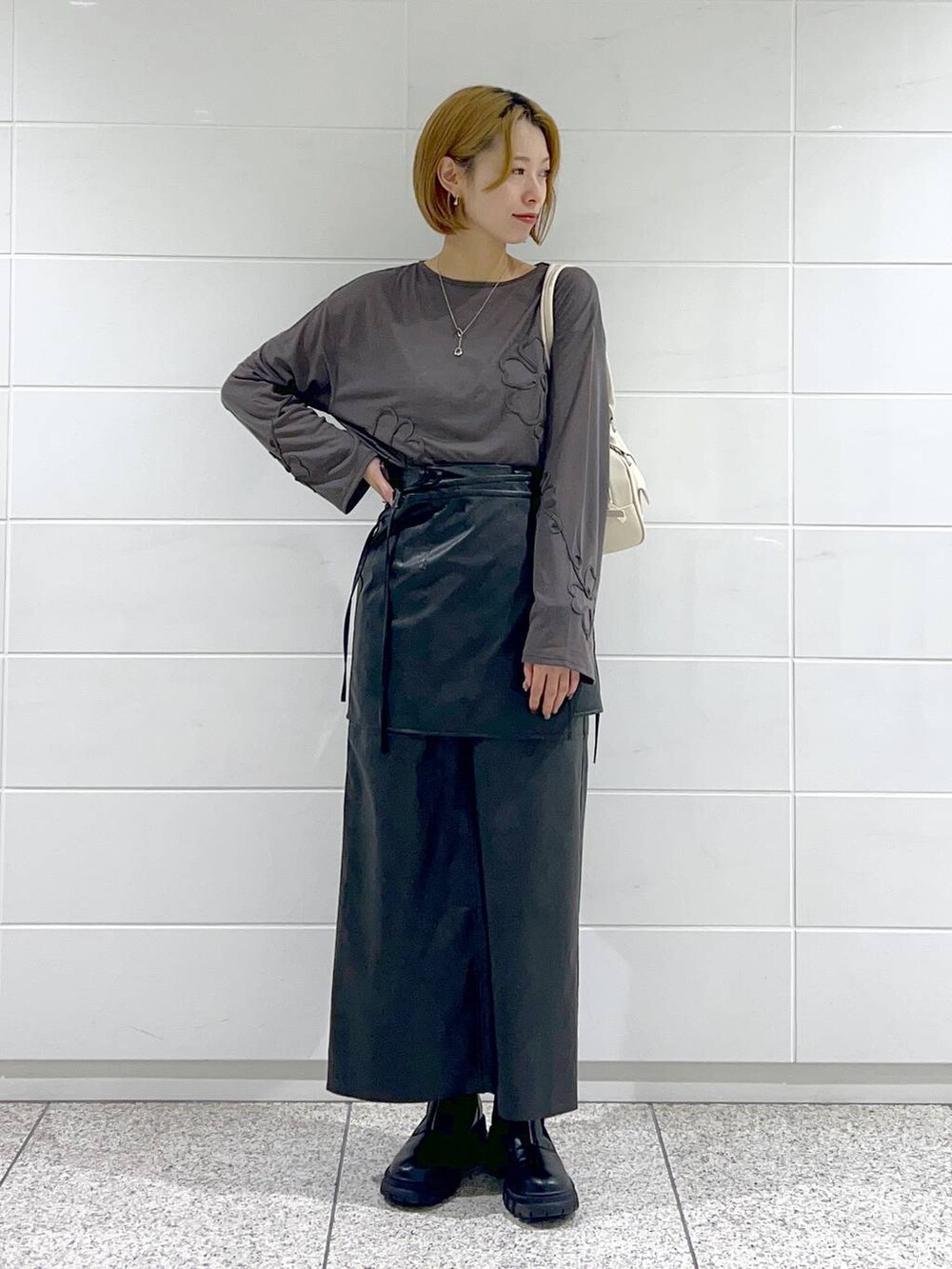 ブラック系のブーツ、グレー系のTシャツ/カットソー、ブラック系のスカートを着用したレディースの秋コーディネートの2枚目の写真