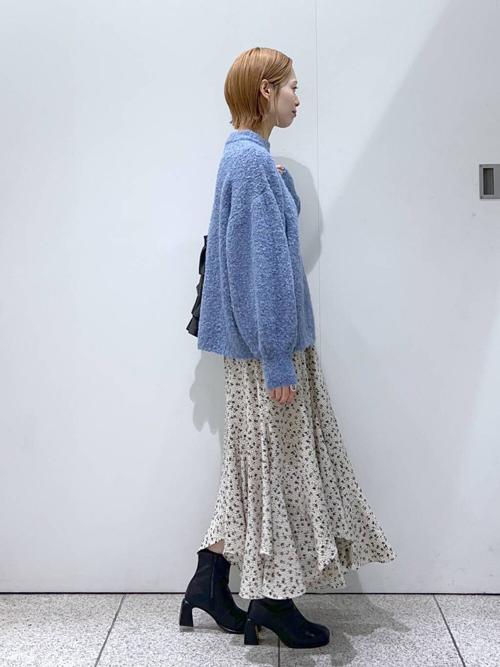 ブラック系のブーツ、ブルー系のニット/セーター、ホワイト系のスカートを着用したレディースの冬コーディネートの6枚目の写真