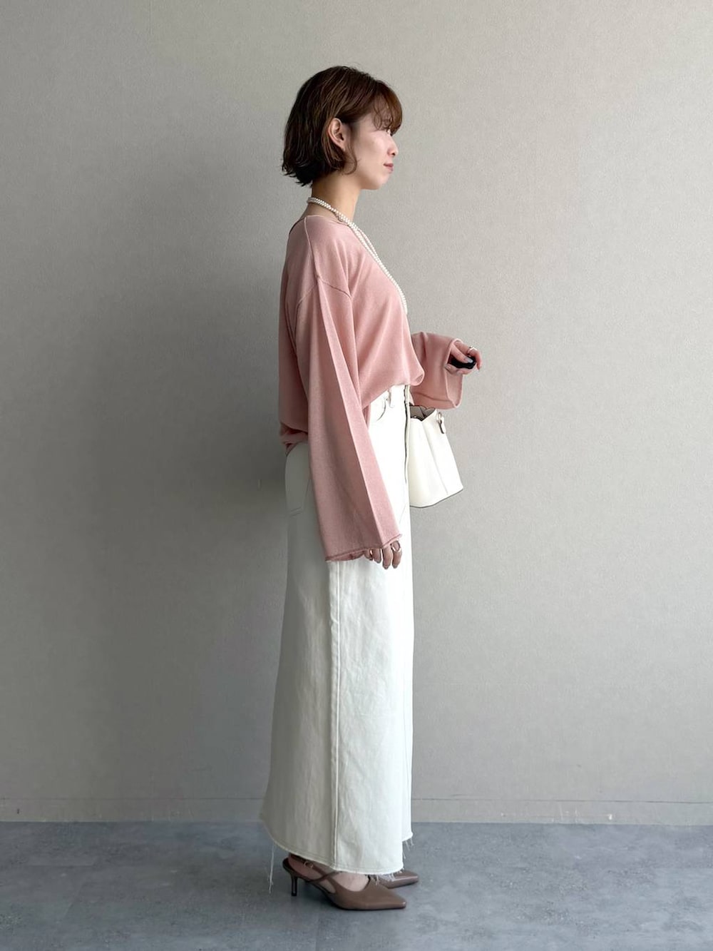 ピンク系のニット/セーター、ブラウン系のサンダル、ホワイト系のスカートを着用したレディースの春コーディネートの2枚目の写真