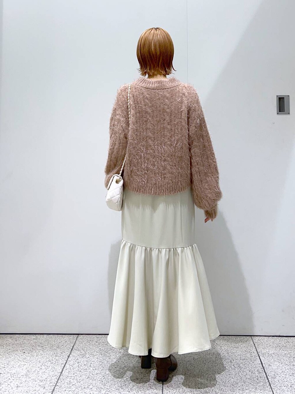 ホワイト系のショルダーバッグ、ブラウン系のブーツ、ブラウン系のニット/セーターを着用したレディースの冬コーディネートの3枚目の写真