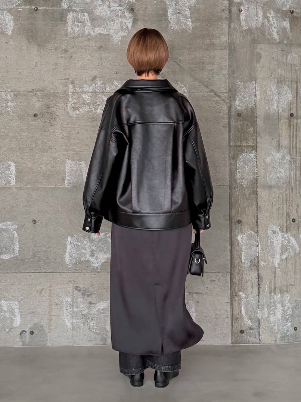 ブラック系のショルダーバッグ、ブラック系のデニムパンツ、ブラック系のパンプスを着用したレディースの冬コーディネートの4枚目の写真