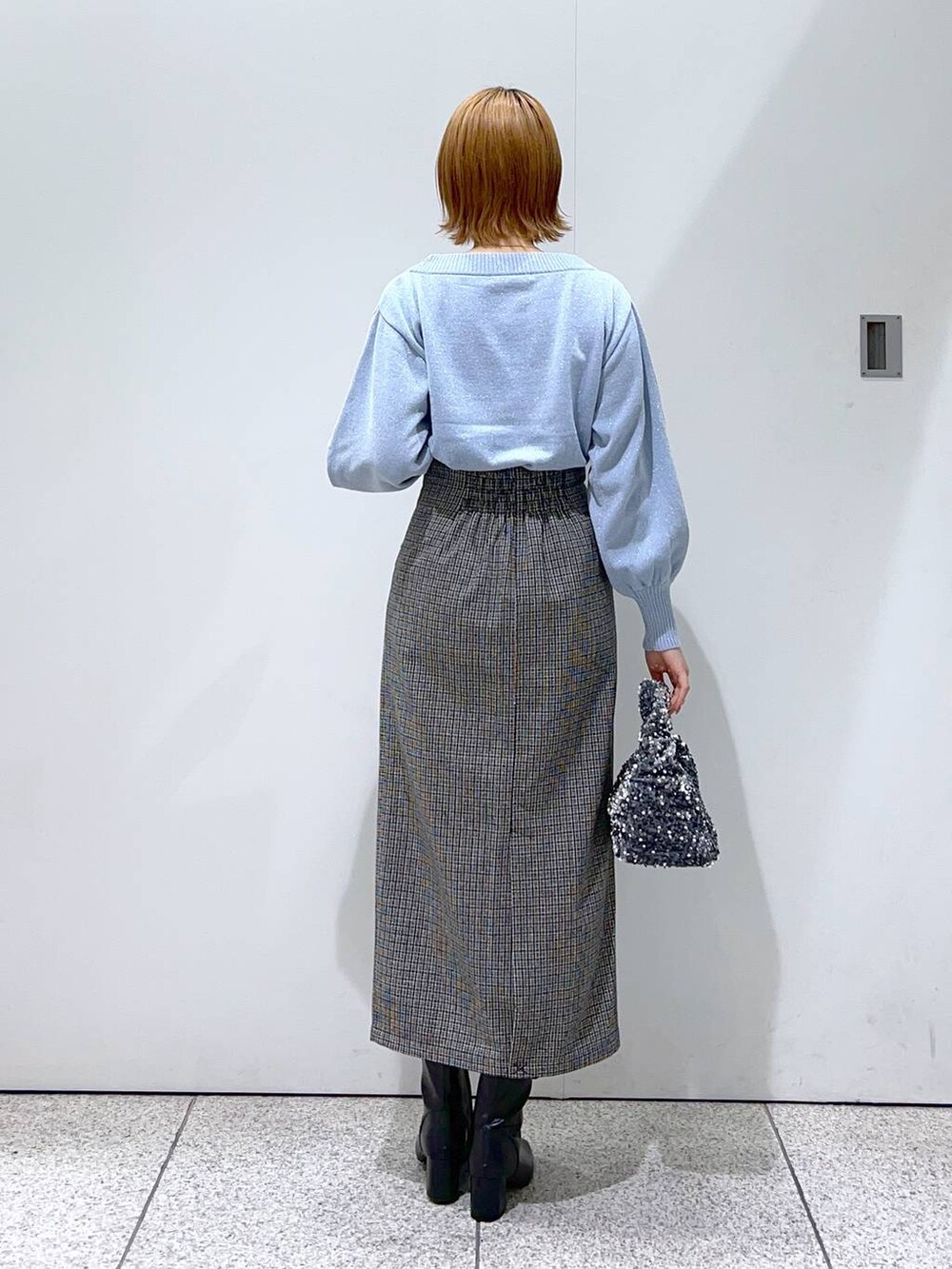 ブルー系のニット/セーター、ホワイト系のノーカラーコート、ブラック系のブーツを着用したレディースの冬コーディネートの6枚目の写真