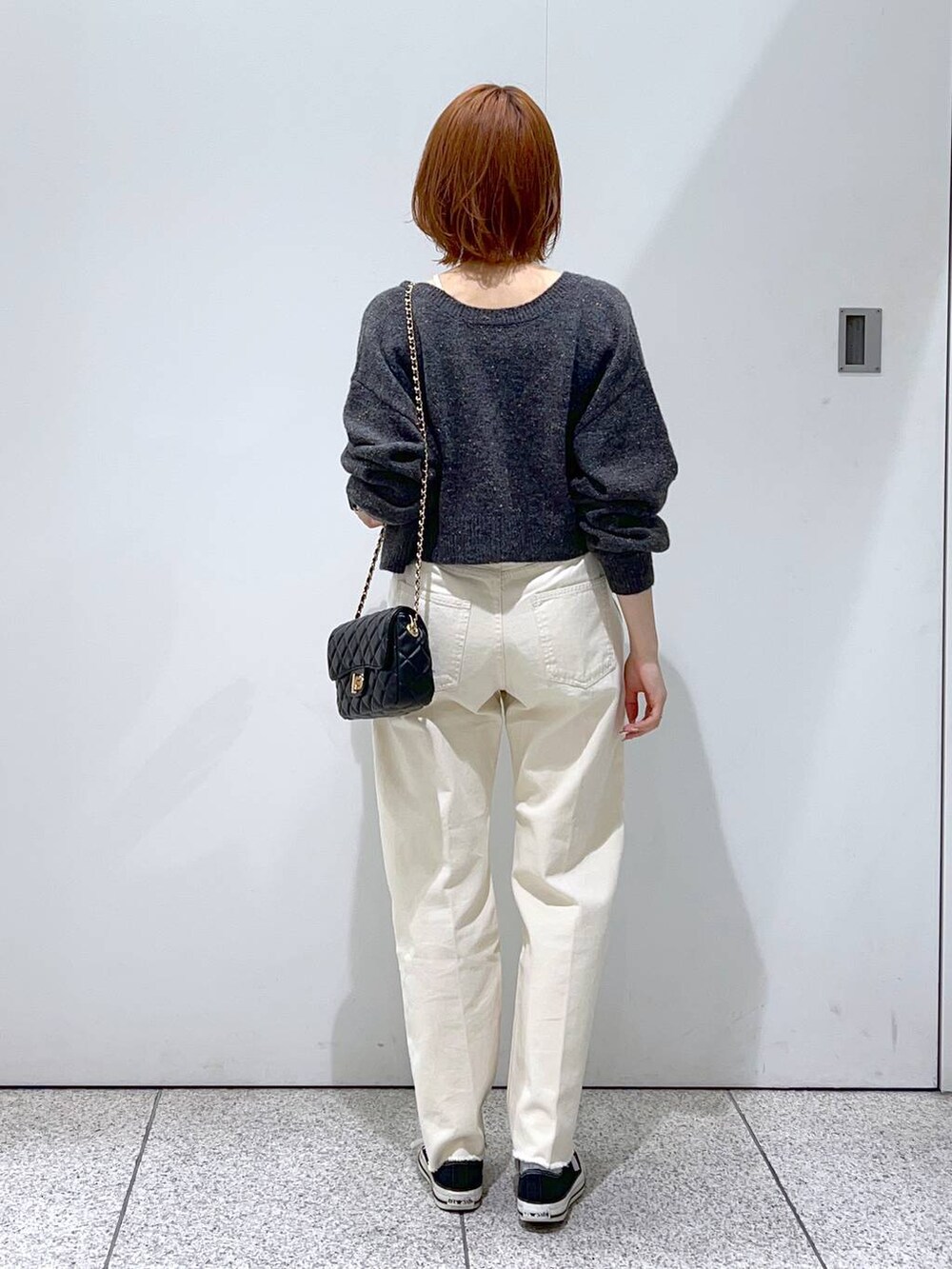 ブラック系のショルダーバッグ、ホワイト系のデニムパンツ、ホワイト系のニット/セーターを着用したレディースの秋コーディネートの3枚目の写真