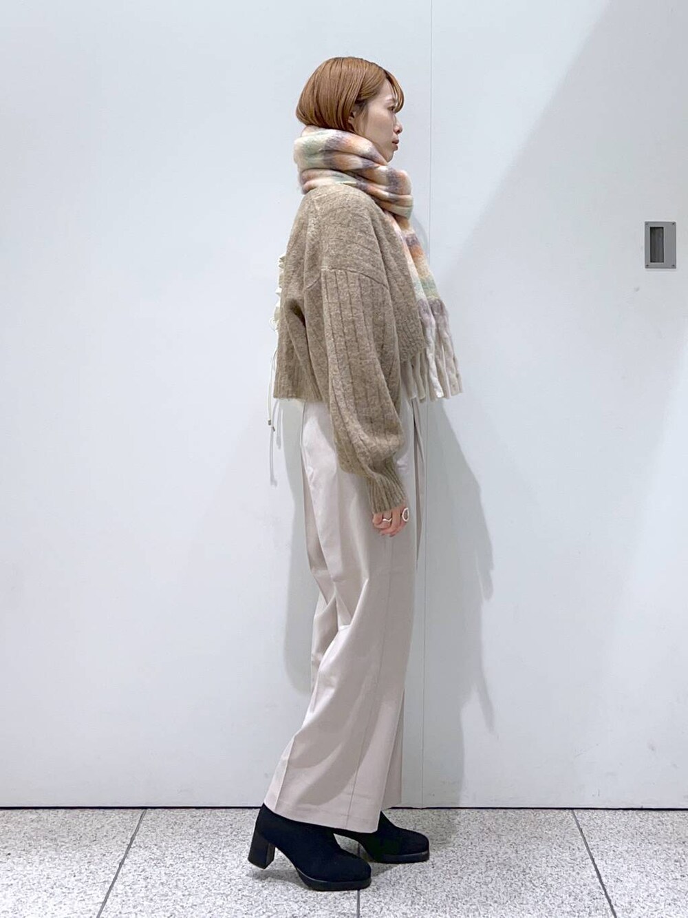 ホワイト系のハンドバッグ、ブラック系のブーツ、ホワイト系のその他パンツを着用したレディースの秋コーディネートの2枚目の写真