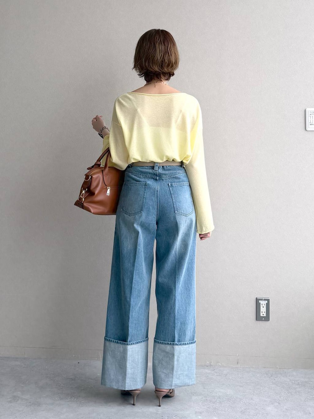 イエロー系のニット/セーター、ブラウン系のボストンバッグ、ベージュ系のトレンチコートを着用したレディースの冬コーディネートの7枚目の写真