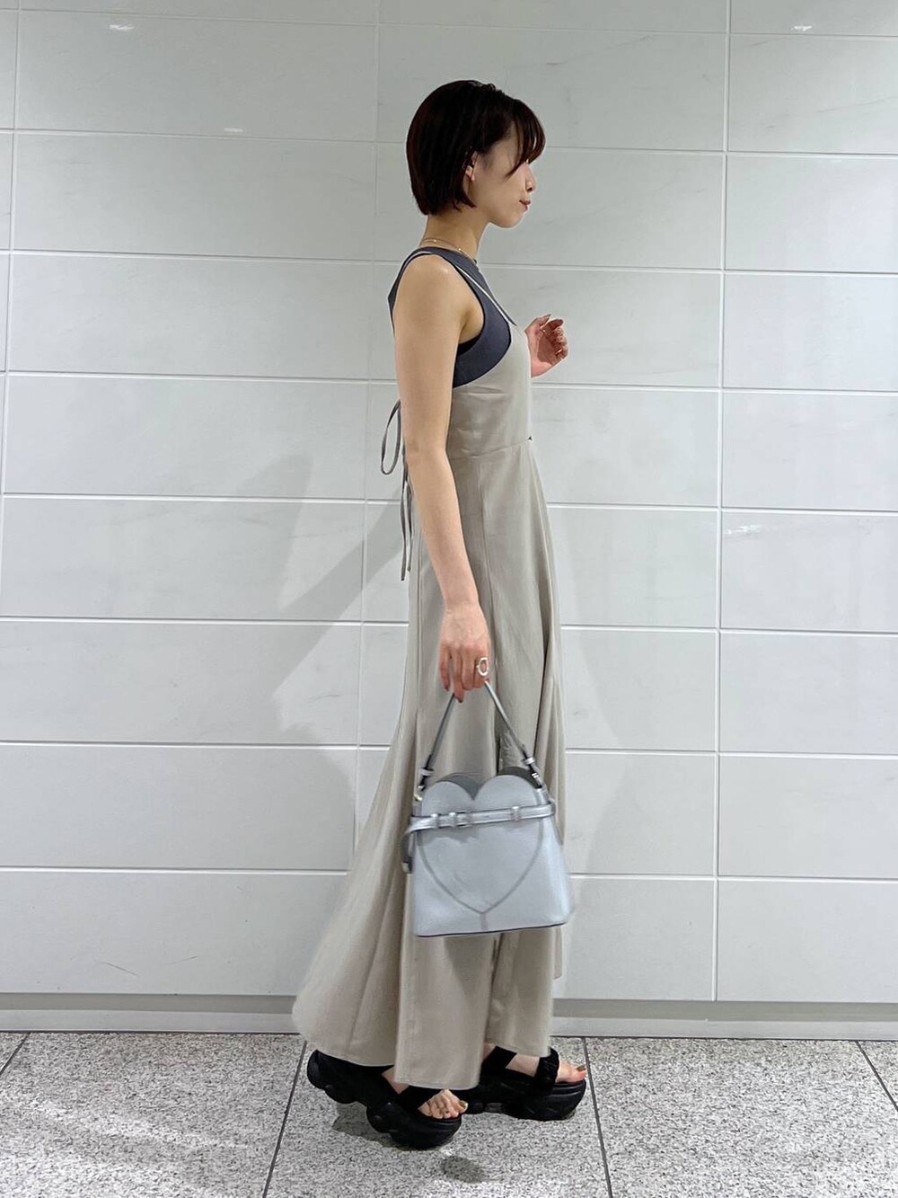 ブラック系のブルゾン、シルバー系のショルダーバッグ、ベージュ系のワンピースを着用したレディースの夏コーディネートの5枚目の写真